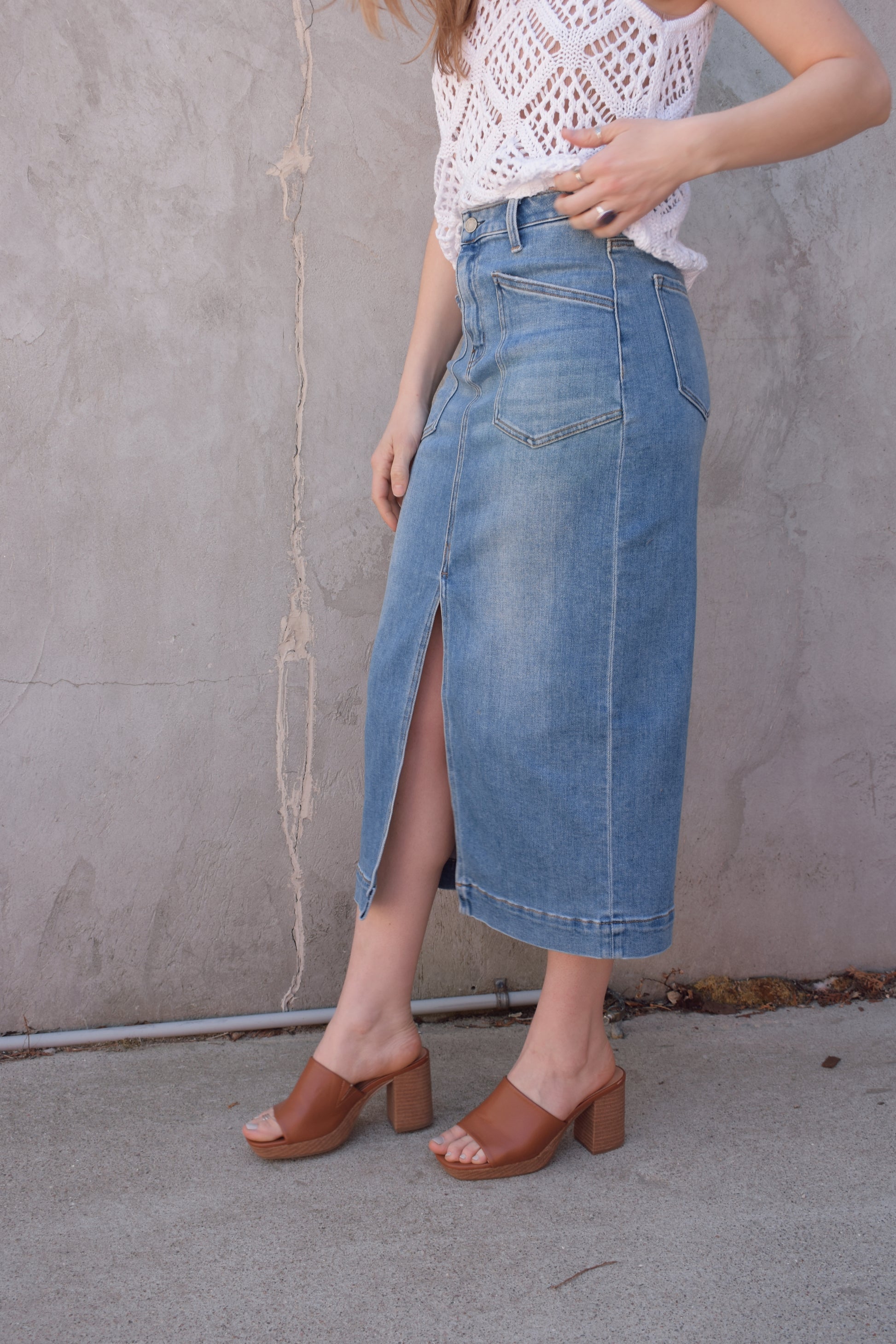 utility stretch denim midi skirt with front slit medium wash large patch pockets on front with angled entry has back pockets and belt loops zip and button enclosure
