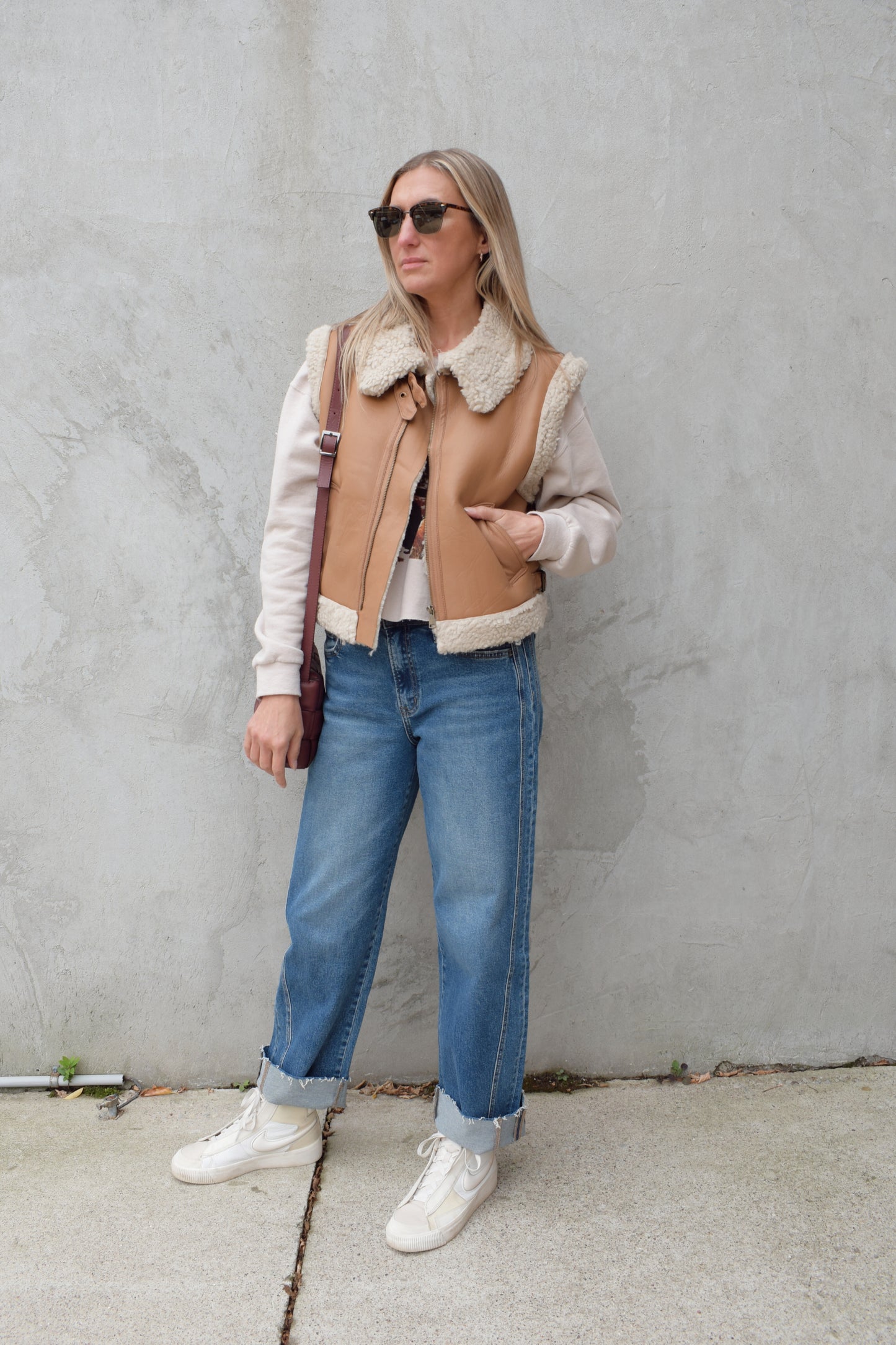 ivory sherpa lined faux camel colored leather moto vest with fold over collar, sherpa exposed along hem and collar, zip enclosure, has pockets, slightly cropped