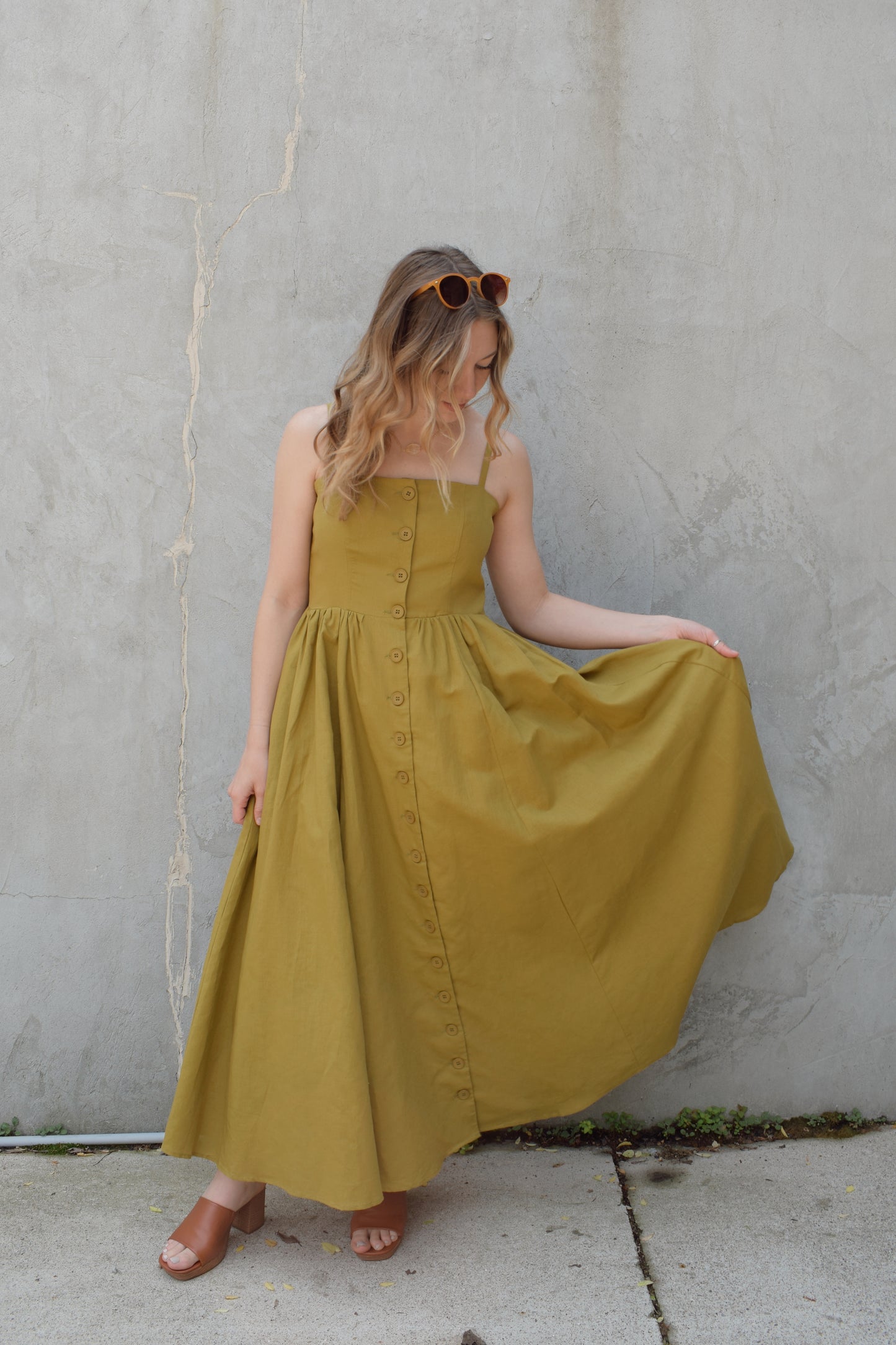 spaghetti strap midi dress with pleats at waistline fitted bodice buttons all down the front that are the same color as the dress, adjustable straps, has pockets, square neckline, smocked panel on back of bodice