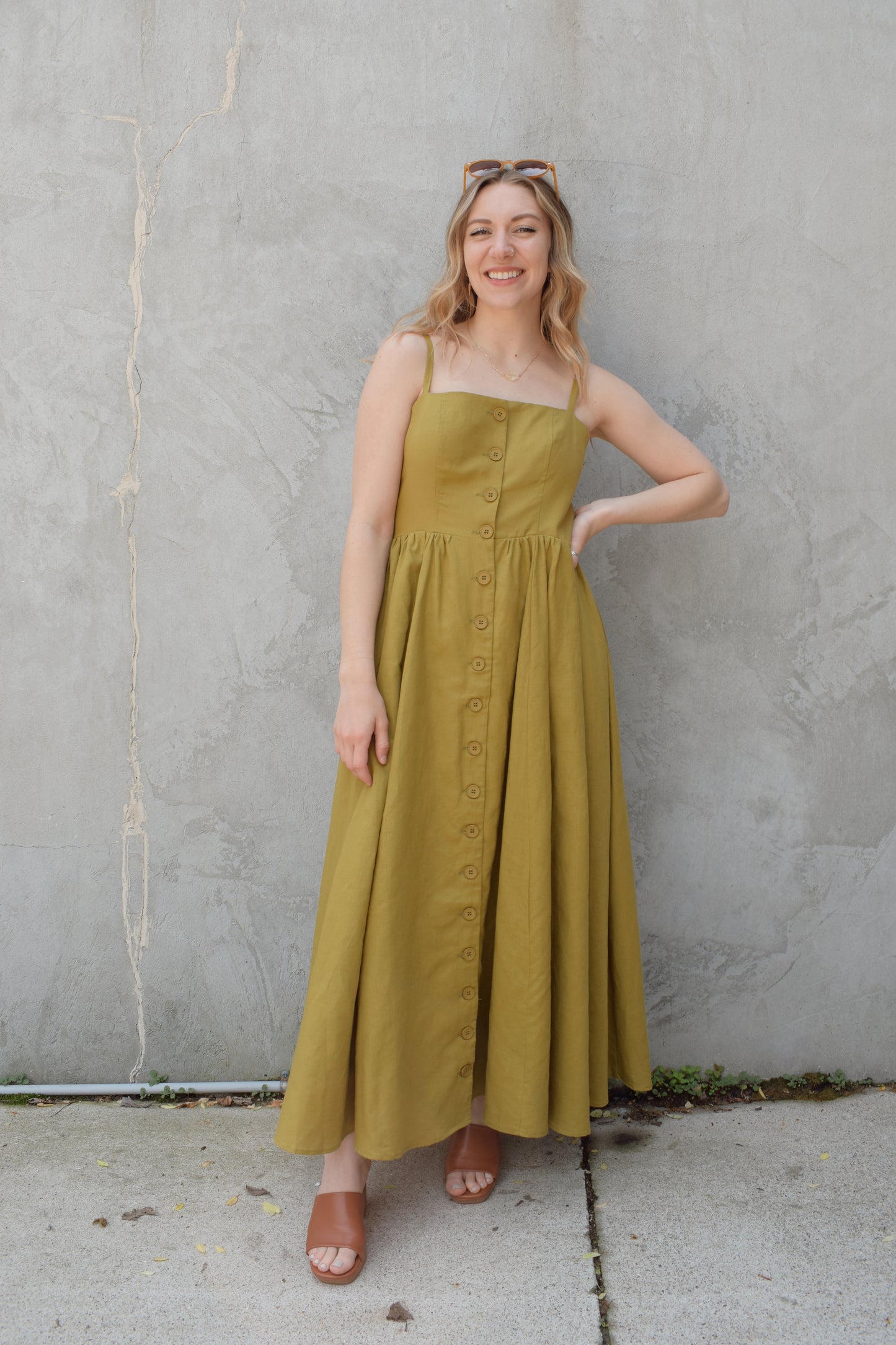 spaghetti strap midi dress with pleats at waistline fitted bodice buttons all down the front that are the same color as the dress, adjustable straps, has pockets, square neckline, smocked panel on back of bodice