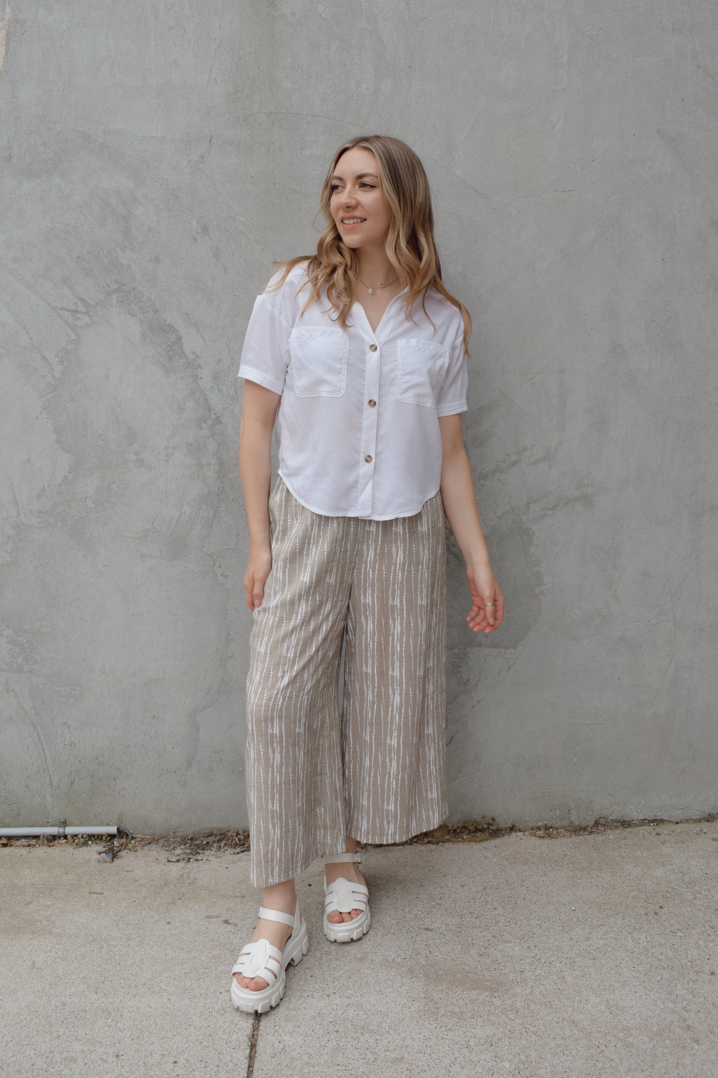 white linen button down, short sleeve, v neck with collar, 3 brown buttons, patch breast pockets, scoop hemline, button detail on back of sleeve cuff