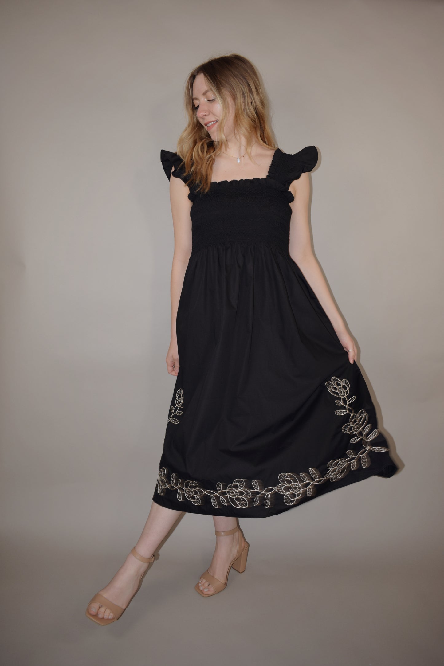 black midi dress with cream embroidered flower vine along hem, smocked bodice, square neckline, flutter shoulder detail, flowy yet tailored feel