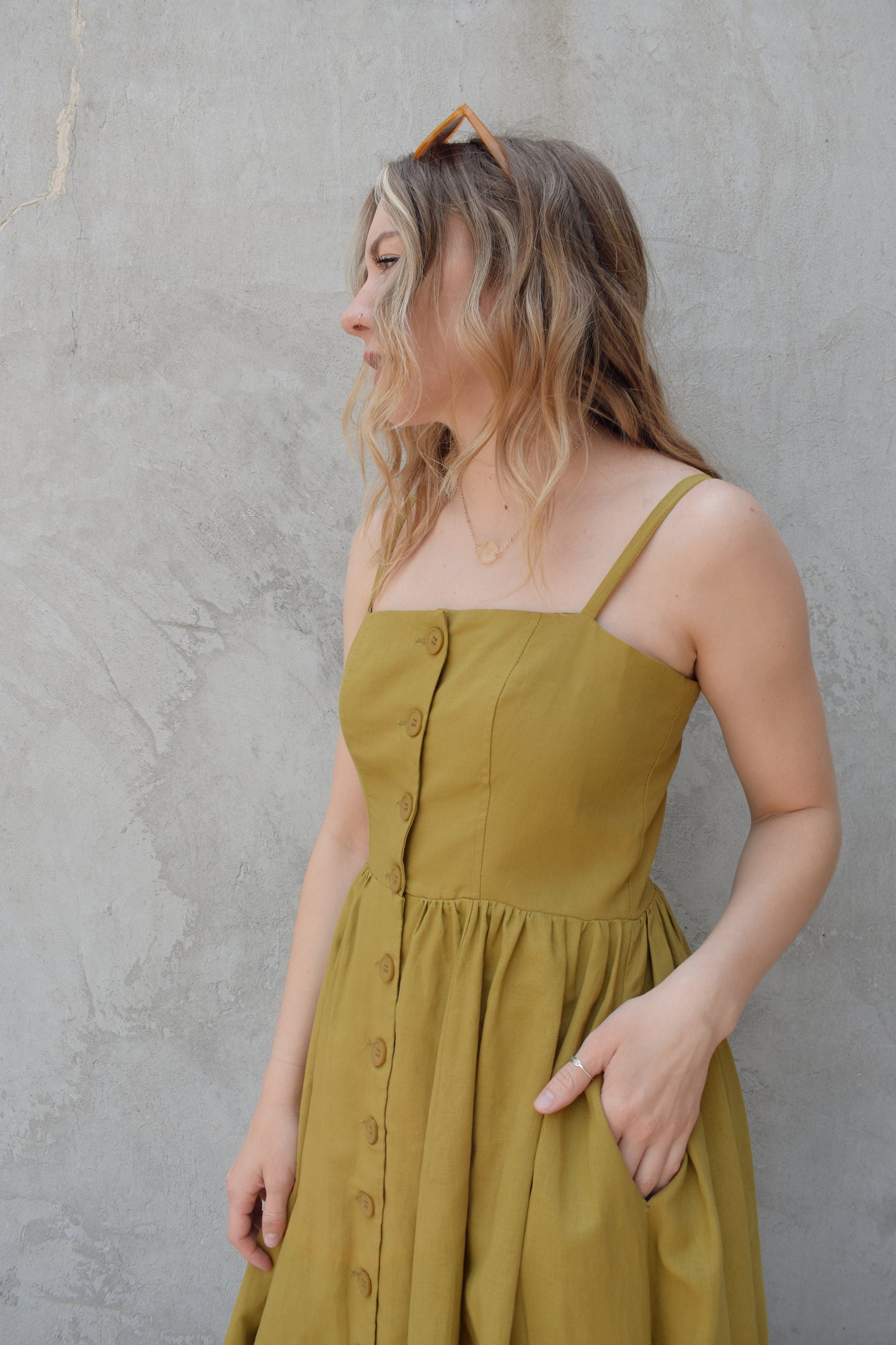 spaghetti strap midi dress with pleats at waistline fitted bodice buttons all down the front that are the same color as the dress, adjustable straps, has pockets, square neckline, smocked panel on back of bodice