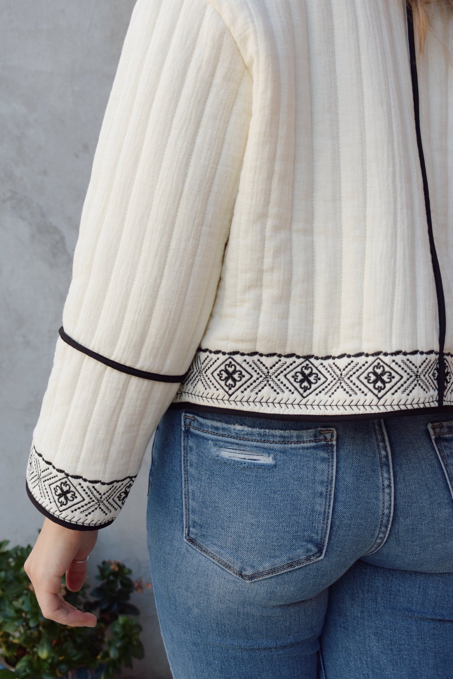 boho quilted ivory jacket with black exposed seam detailing and design along hem, has pockets, 2 clasp enclosure