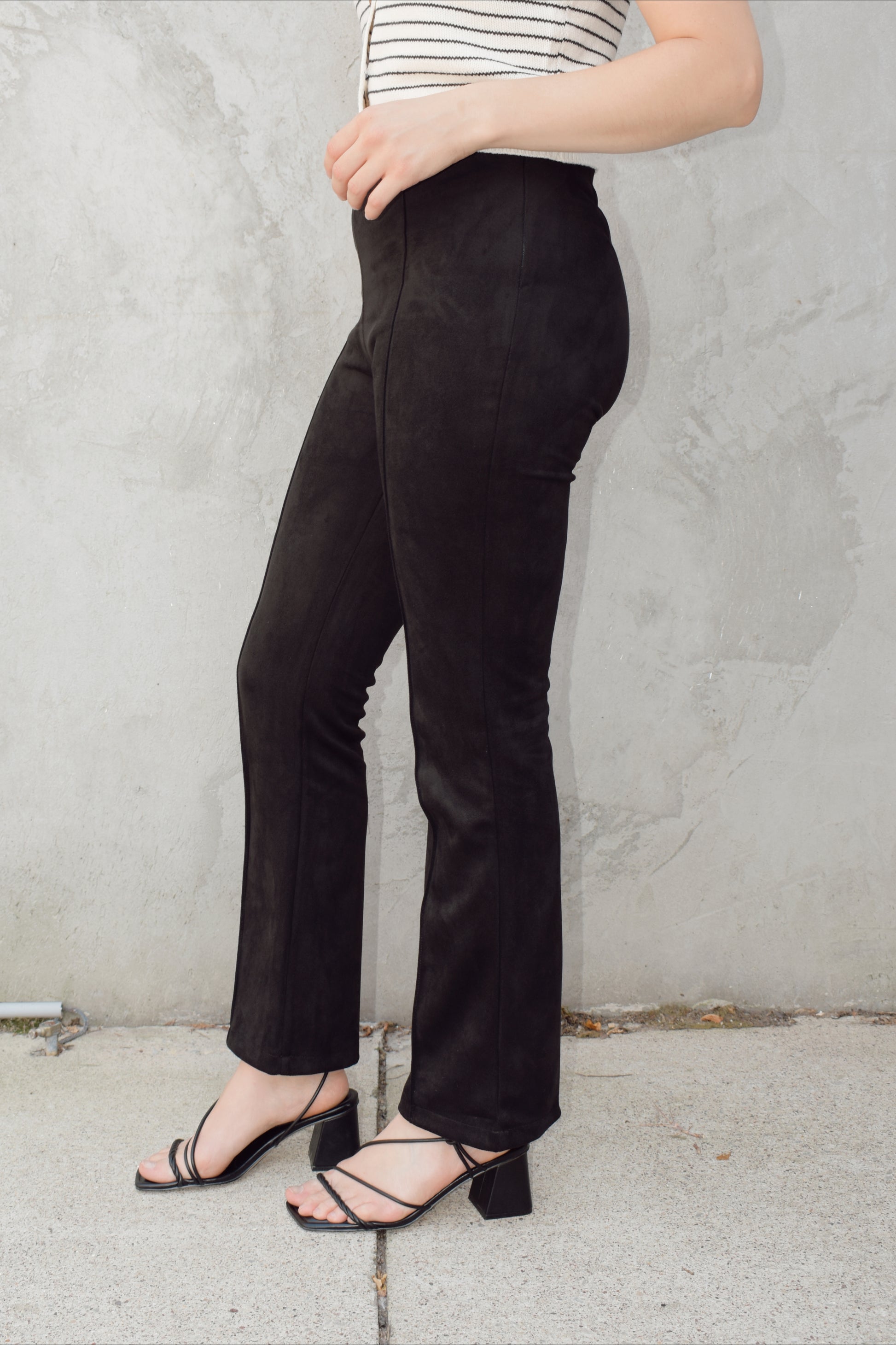 black faux suede pants with a slight cropped kick flare, raised seam detail along front of pant legs, zip side enclosure, high waisted