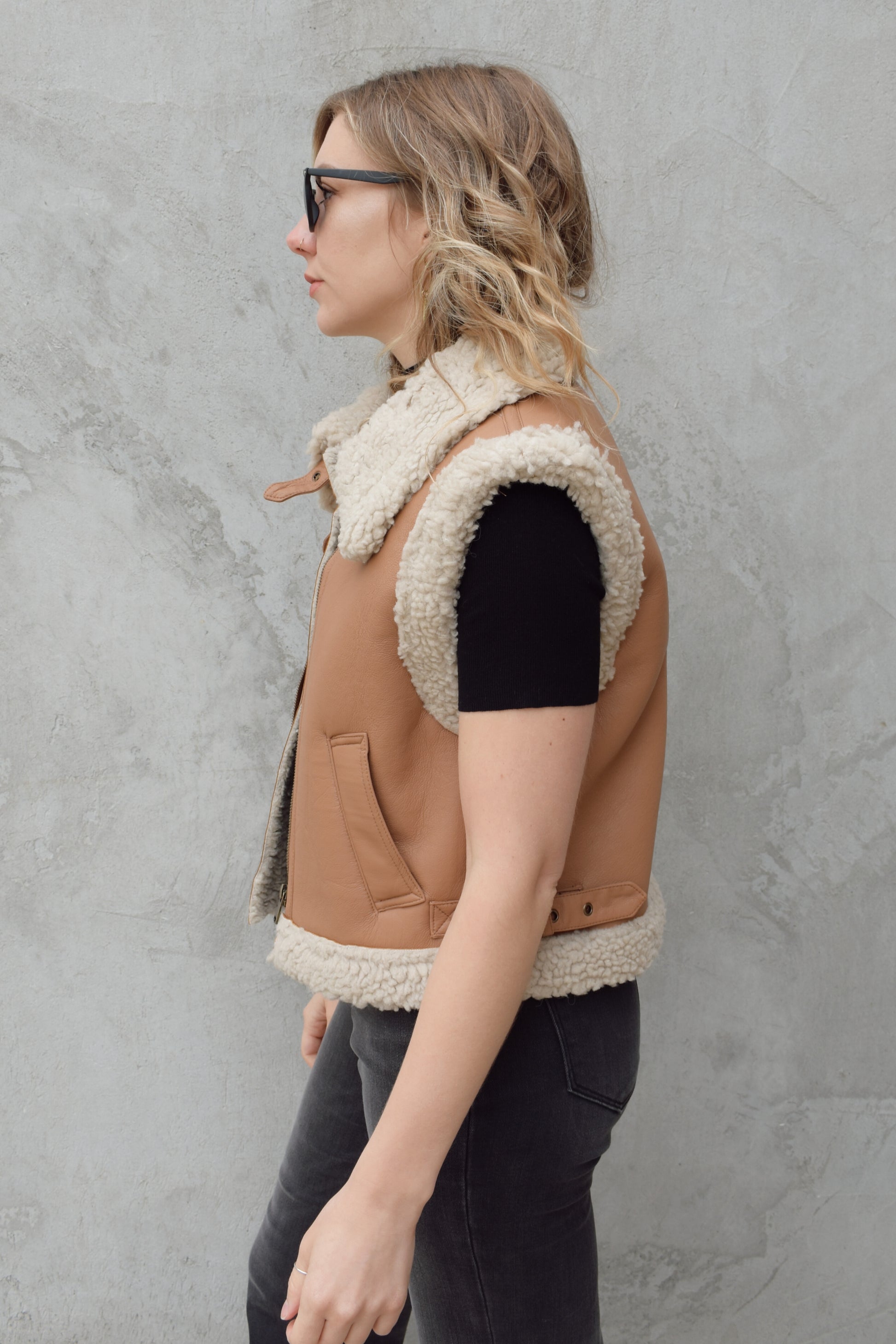 ivory sherpa lined faux camel colored leather moto vest with fold over collar, sherpa exposed along hem and collar, zip enclosure, has pockets, slightly cropped