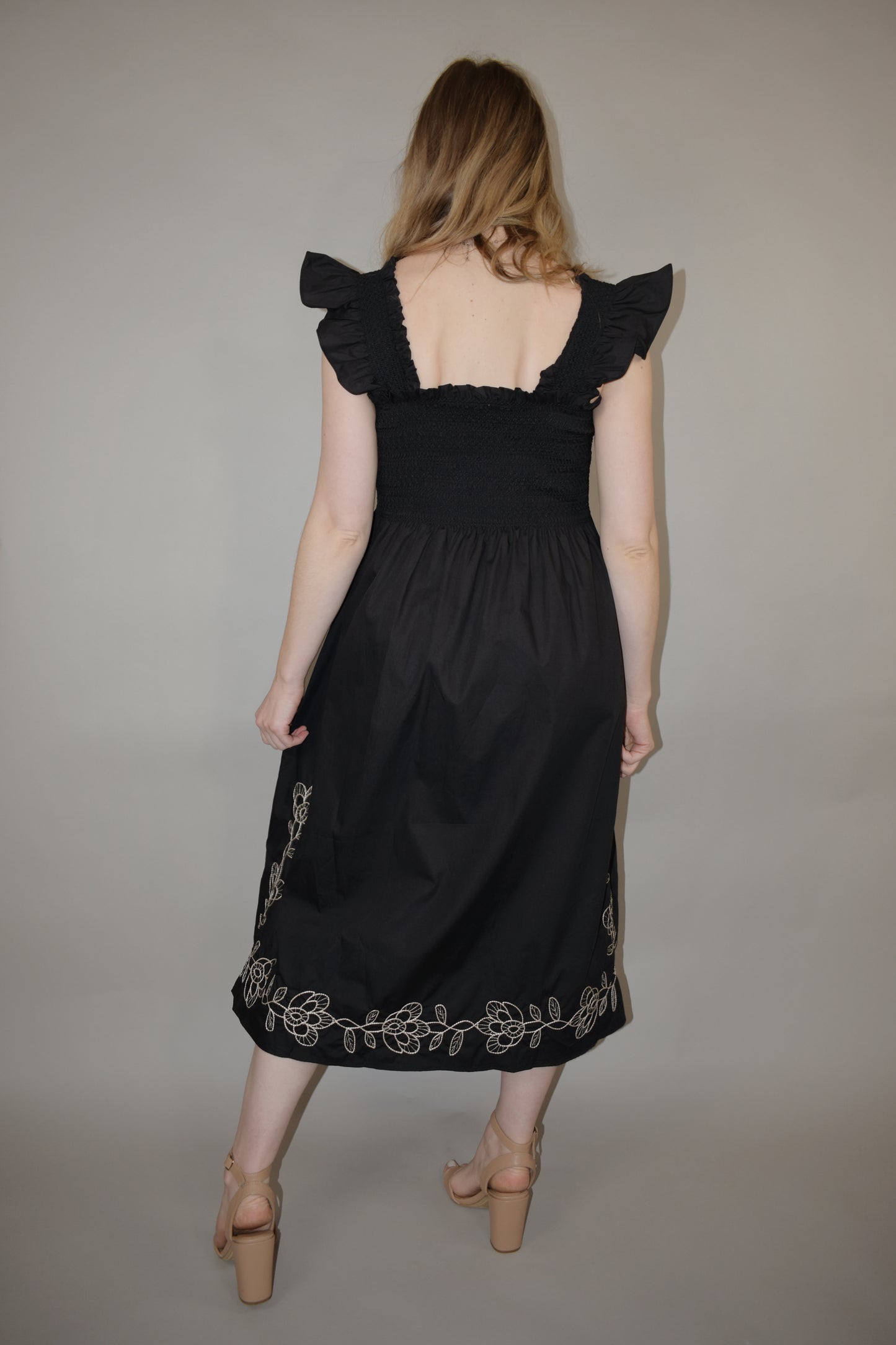 black midi dress with cream embroidered flower vine along hem, smocked bodice, square neckline, flutter shoulder detail, flowy yet tailored feel