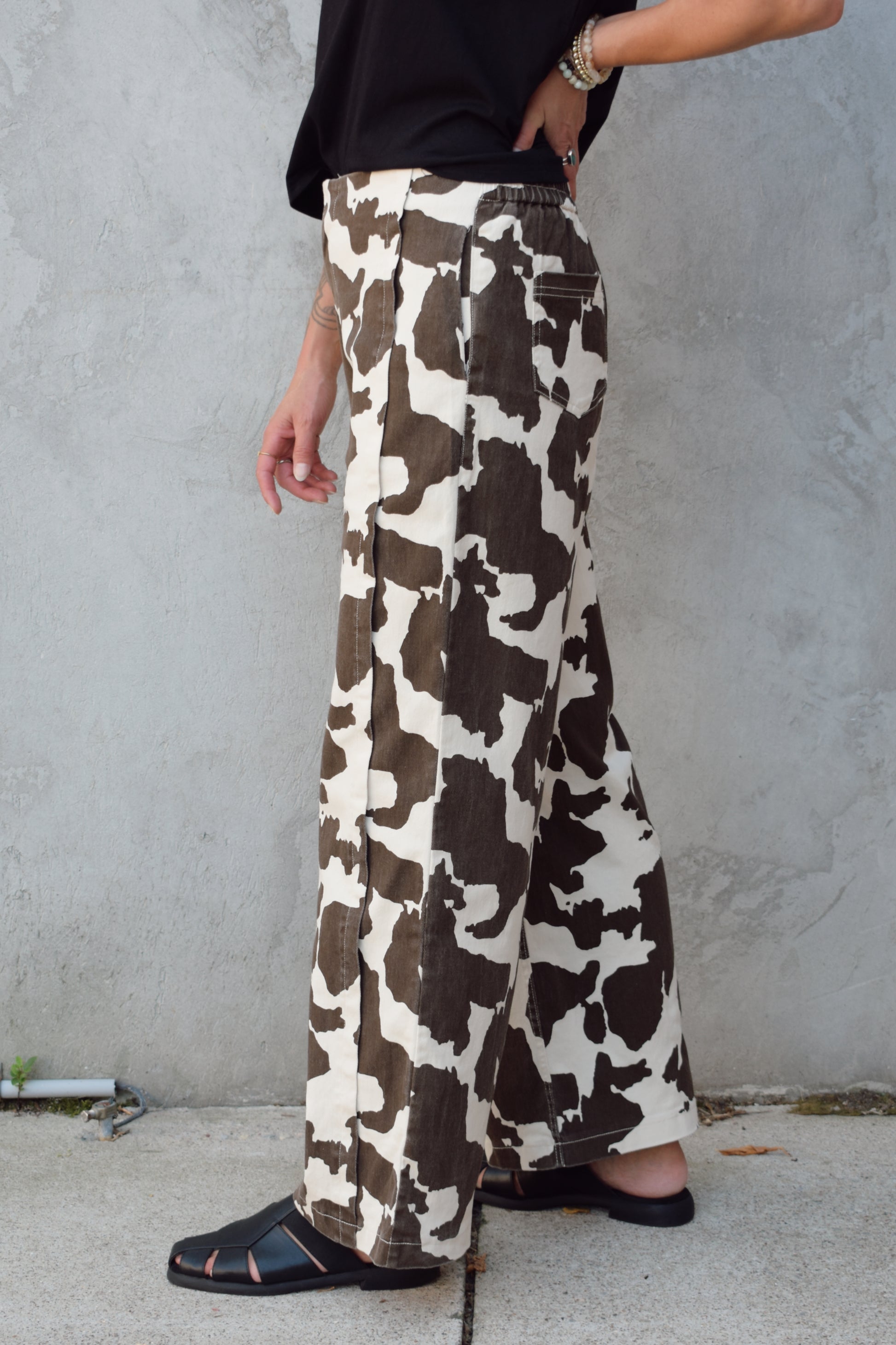high rise cow print pants with zip and clasp enclosure, seam detailing, elastic on back of waistband, wide leg full length, has front pockets and back pockets