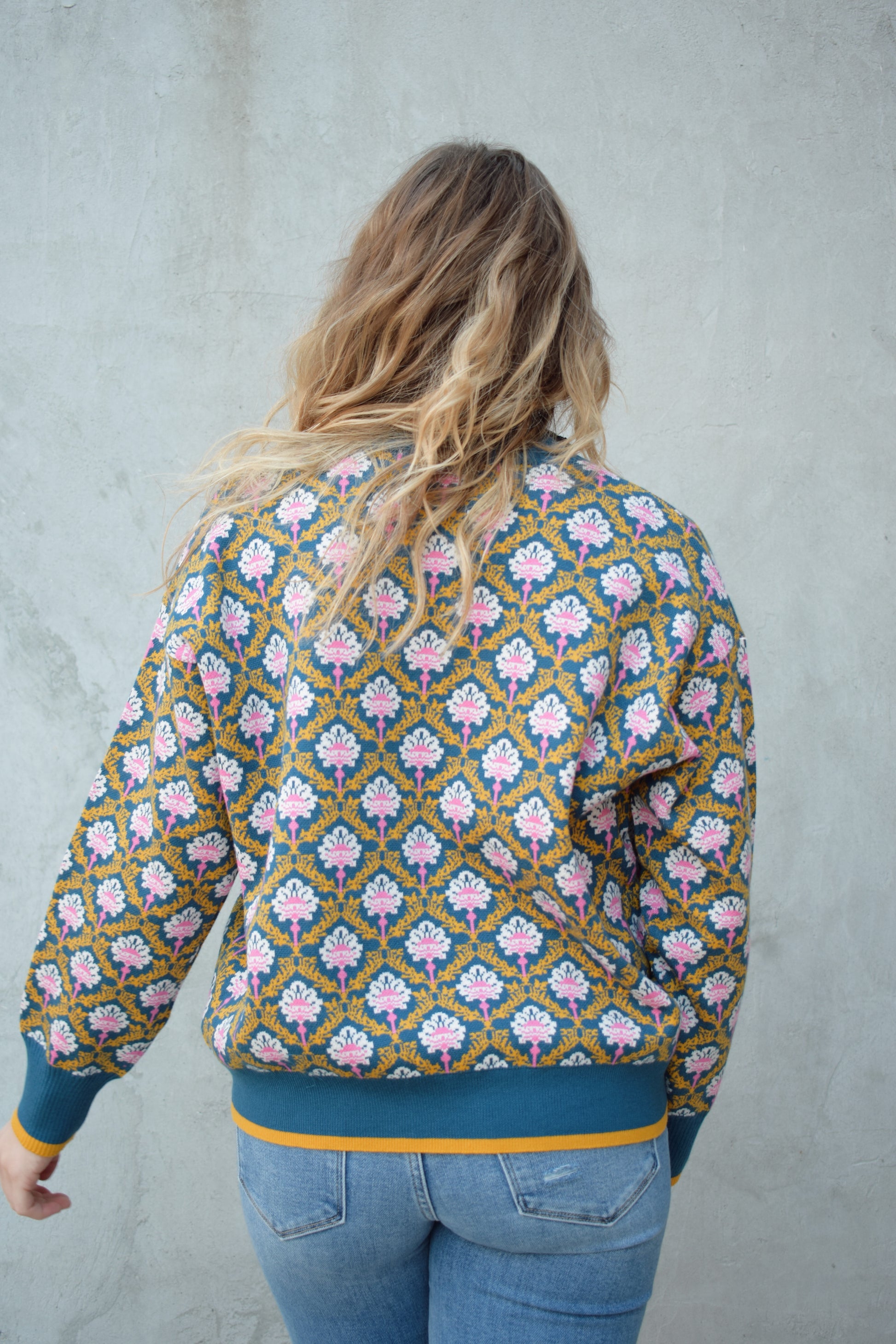 half zip relaxed fit statement pattern pullover with blue and yellow band at ham and cuff and just blue on collar. pattern is yellow, white, and pink on a blue background