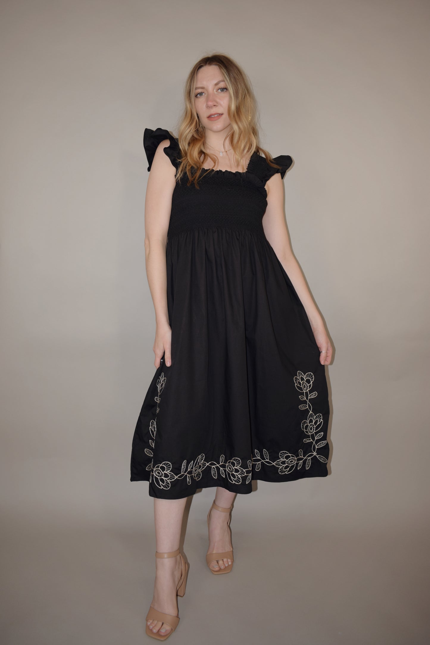 black midi dress with cream embroidered flower vine along hem, smocked bodice, square neckline, flutter shoulder detail, flowy yet tailored feel