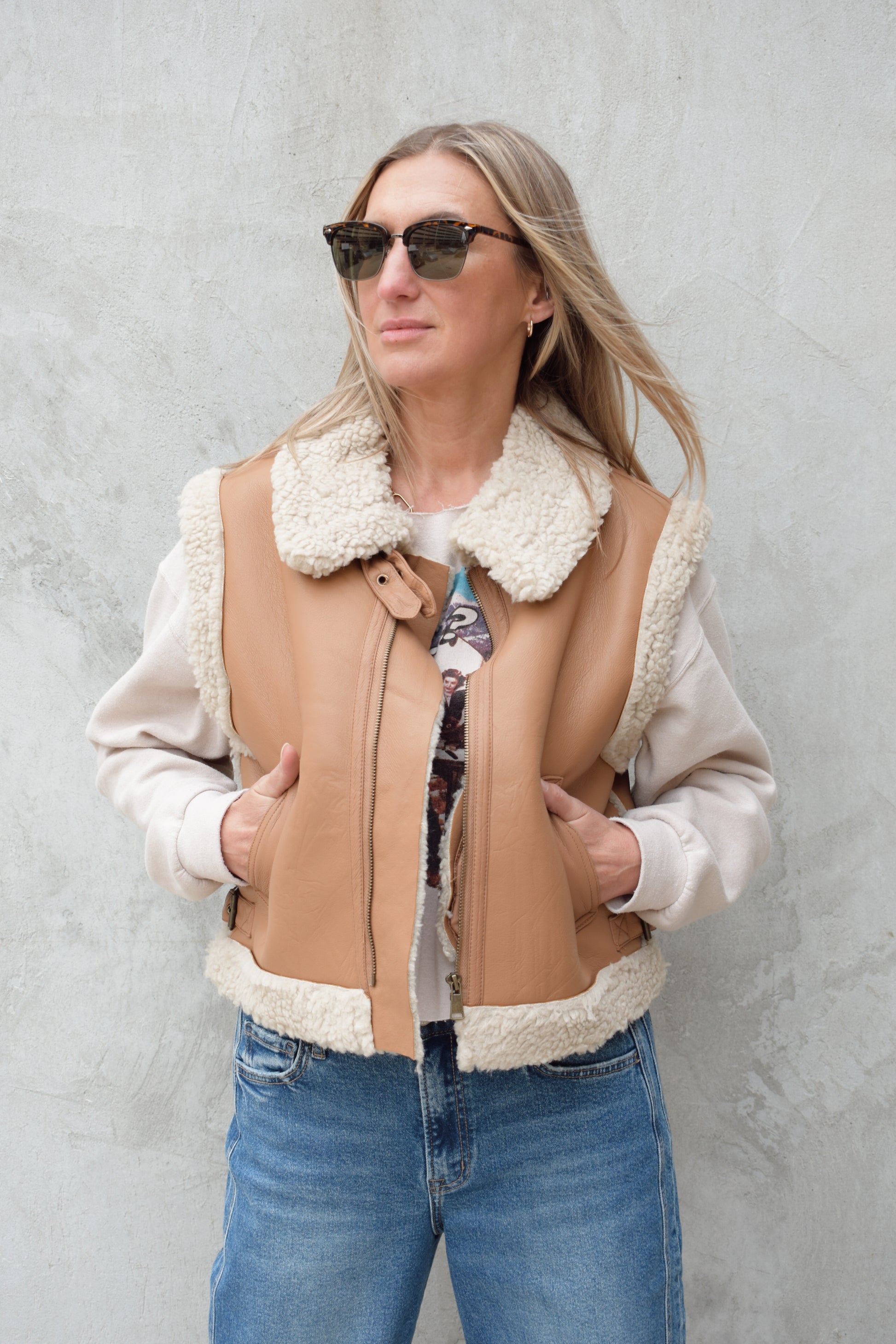ivory sherpa lined faux camel colored leather moto vest with fold over collar, sherpa exposed along hem and collar, zip enclosure, has pockets, slightly cropped