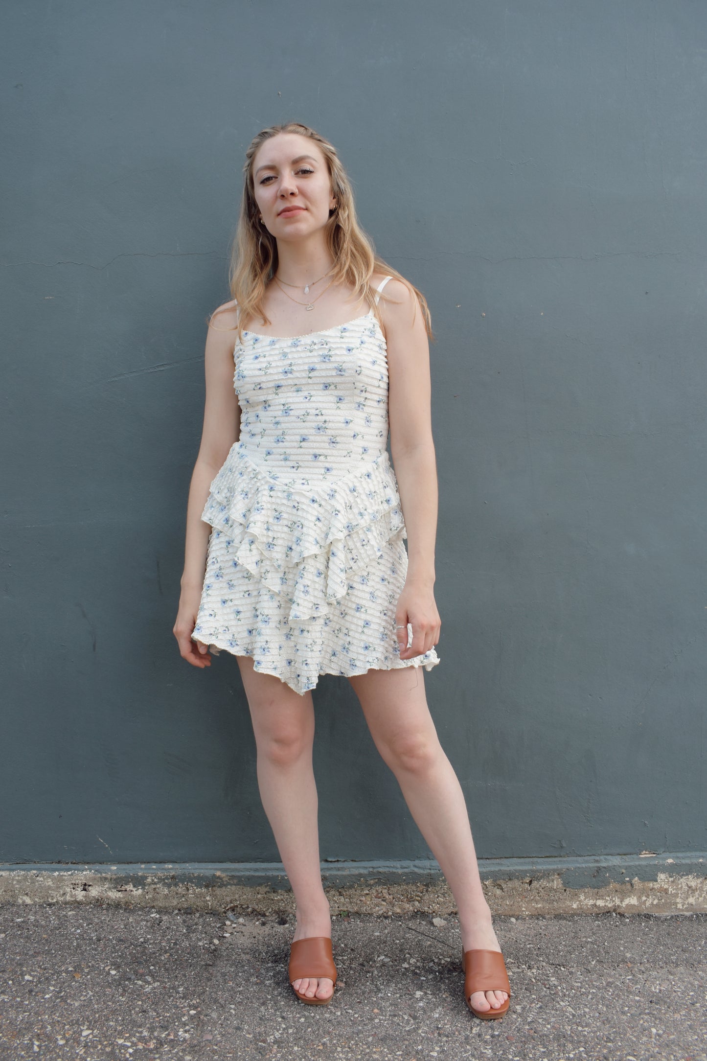 cream mini dress with a blue ditsy floral pattern and mini ruffle fabric, stretchy, back zip enclosure, adjustable spaghetti straps, shark bite tiered skirt, fitted bodice, lined