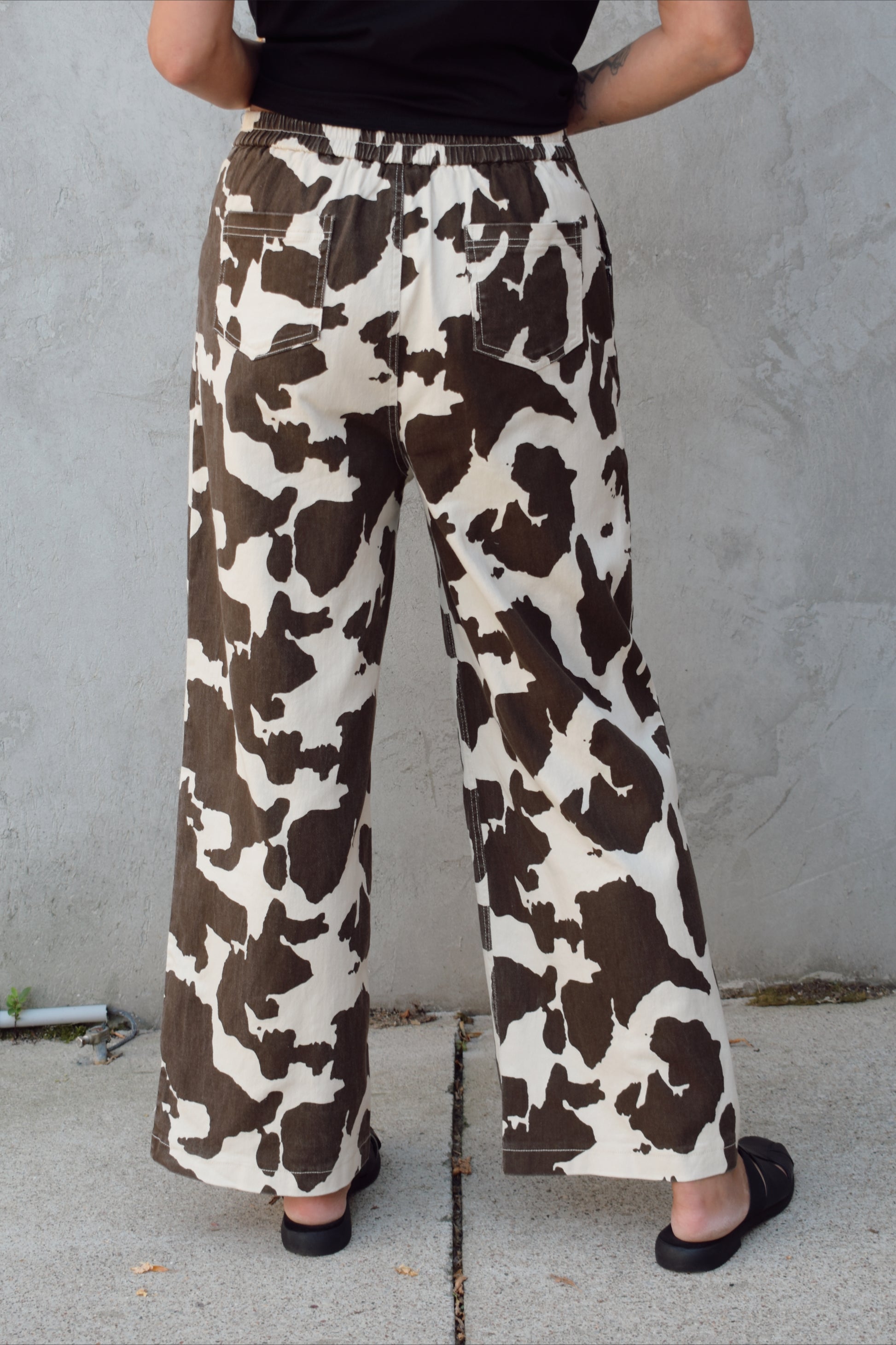 high rise cow print pants with zip and clasp enclosure, seam detailing, elastic on back of waistband, wide leg full length, has front pockets and back pockets