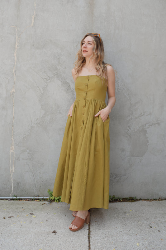 spaghetti strap midi dress with pleats at waistline fitted bodice buttons all down the front that are the same color as the dress, adjustable straps, has pockets, square neckline, smocked panel on back of bodice