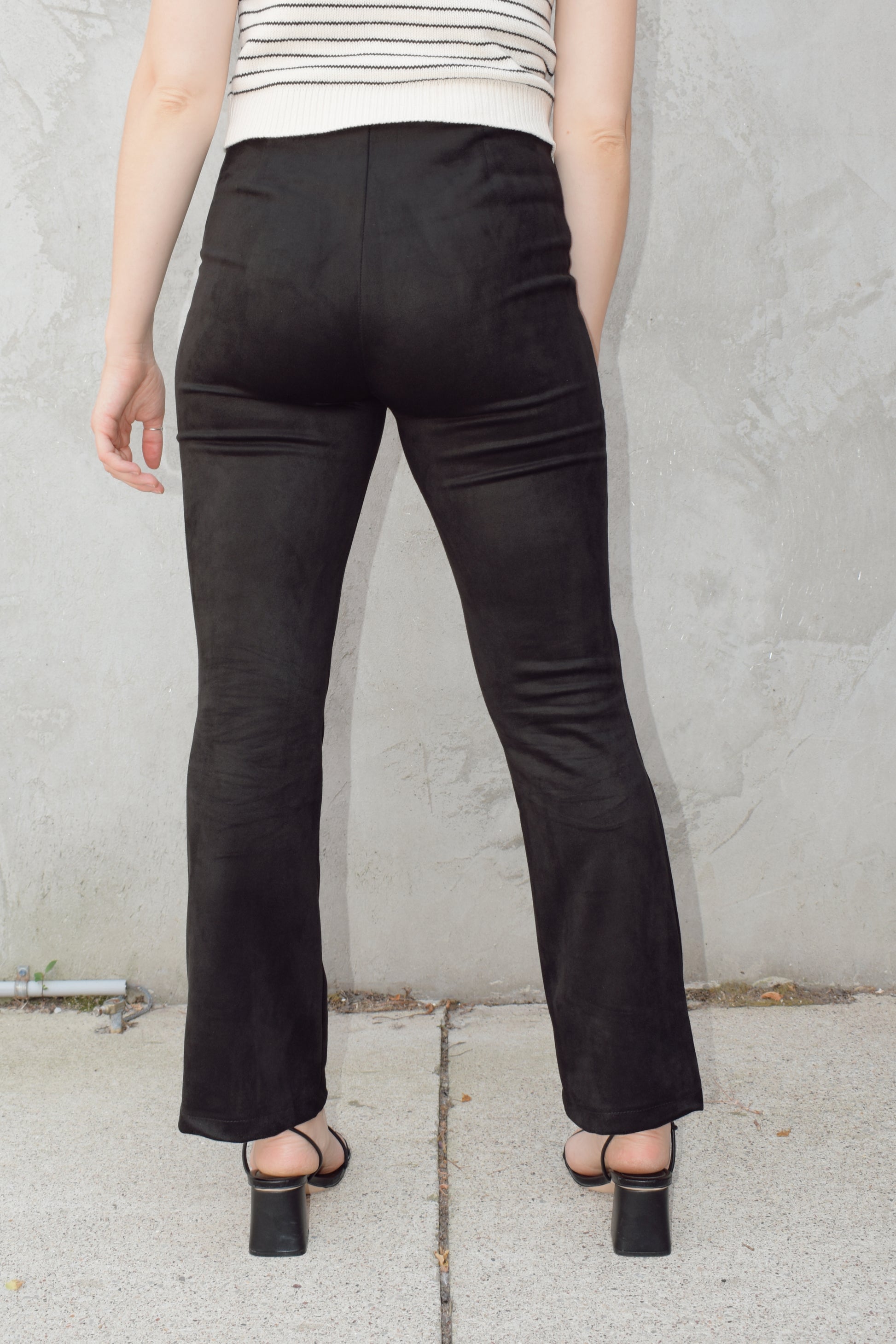 black faux suede pants with a slight cropped kick flare, raised seam detail along front of pant legs, zip side enclosure, high waisted