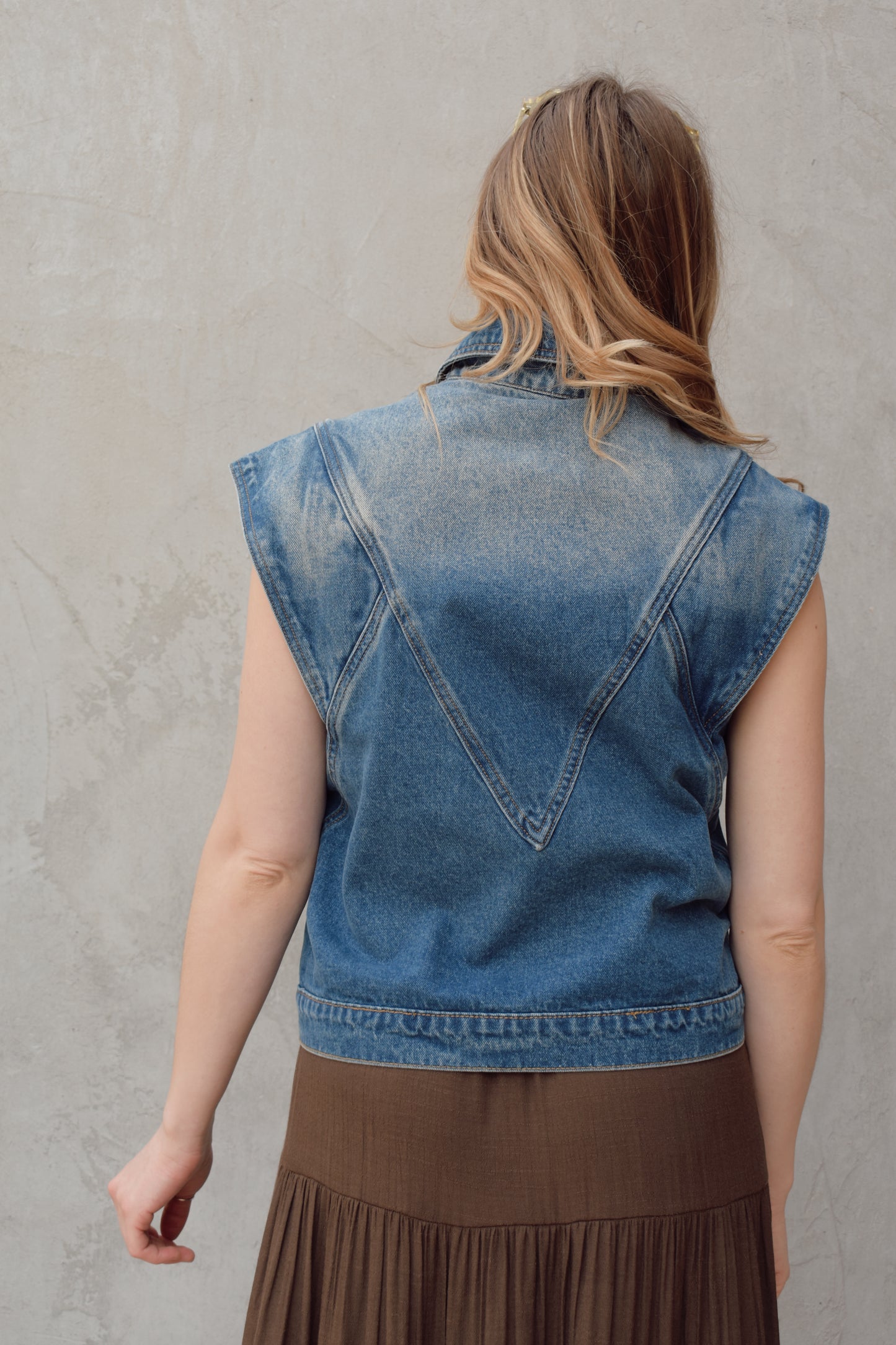 denim full length vest medium wash with some lighter wash marks no holes seam details along front side and back has slit pockets front button enclosure and structured shoulders