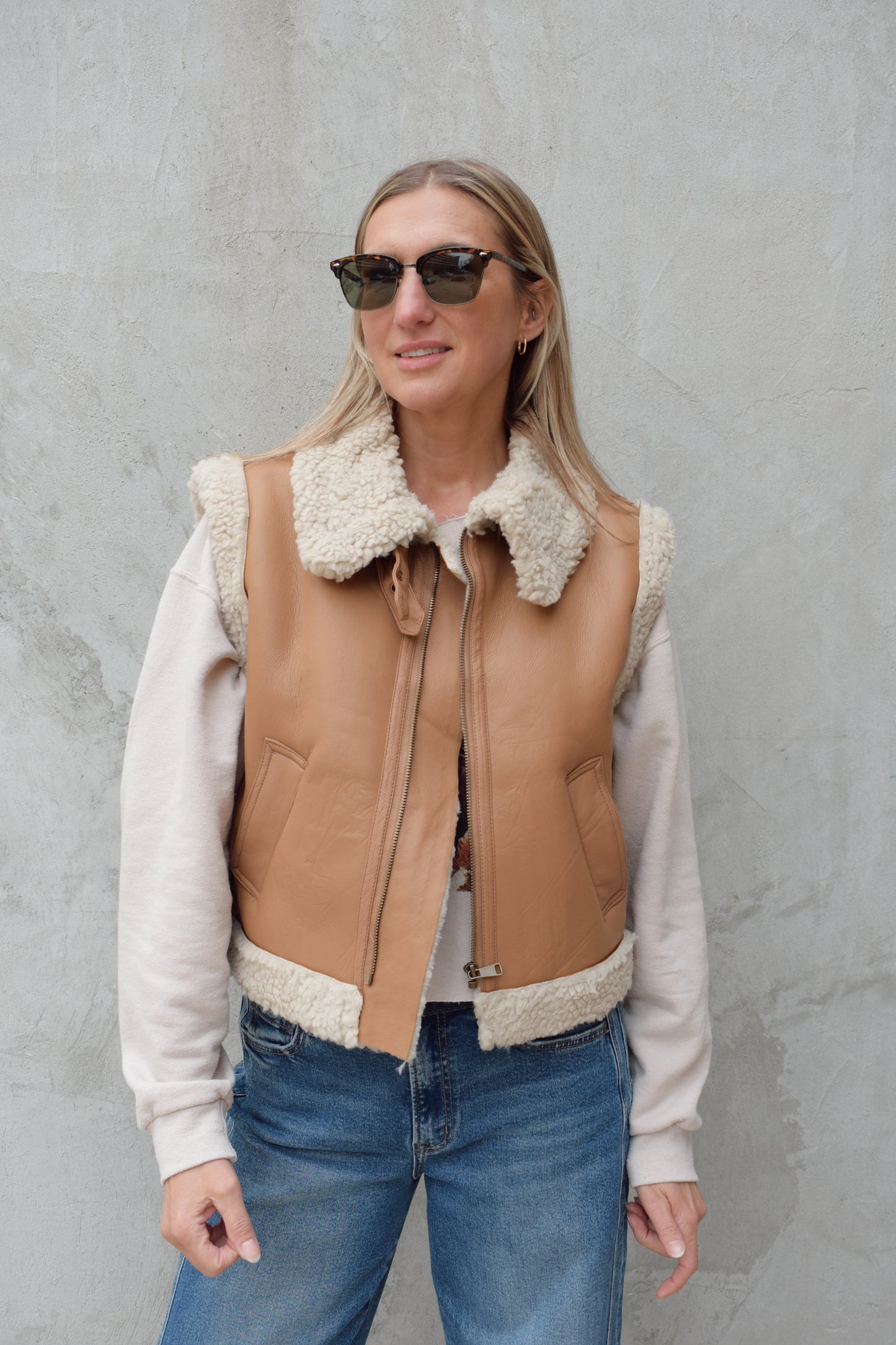 ivory sherpa lined faux camel colored leather moto vest with fold over collar, sherpa exposed along hem and collar, zip enclosure, has pockets, slightly cropped