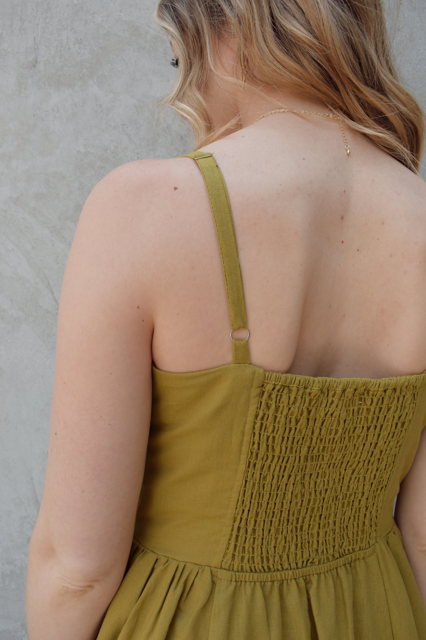 spaghetti strap midi dress with pleats at waistline fitted bodice buttons all down the front that are the same color as the dress, adjustable straps, has pockets, square neckline, smocked panel on back of bodice