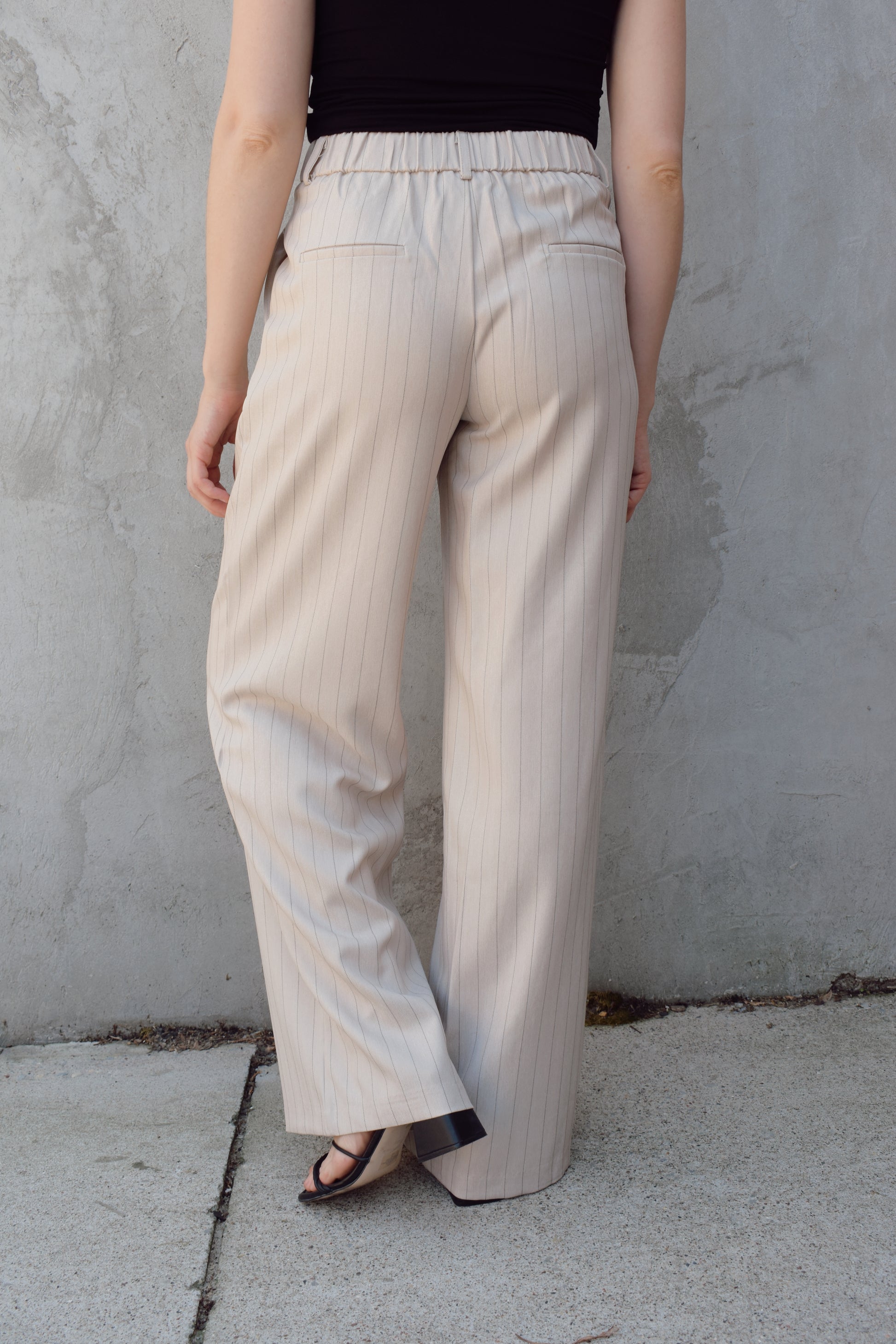 vertical pinstripe trousers with front pleats, pockets, zip and button enclosure, has beltloops, fake back pockets, elastic on back of waistband, full length
