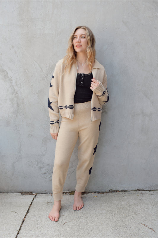 cream zip up sweater jacket with dark blue moon and stars on sleeves and trim design, collared neckline, ribbed hem and cuffs, side pockets, drop shoulders, relaxed fit