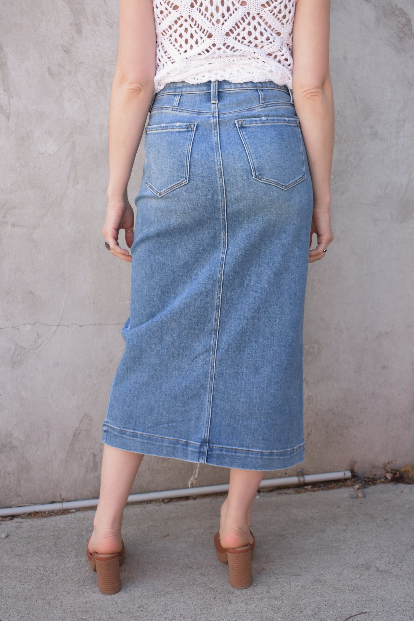 utility stretch denim midi skirt with front slit medium wash large patch pockets on front with angled entry has back pockets and belt loops zip and button enclosure