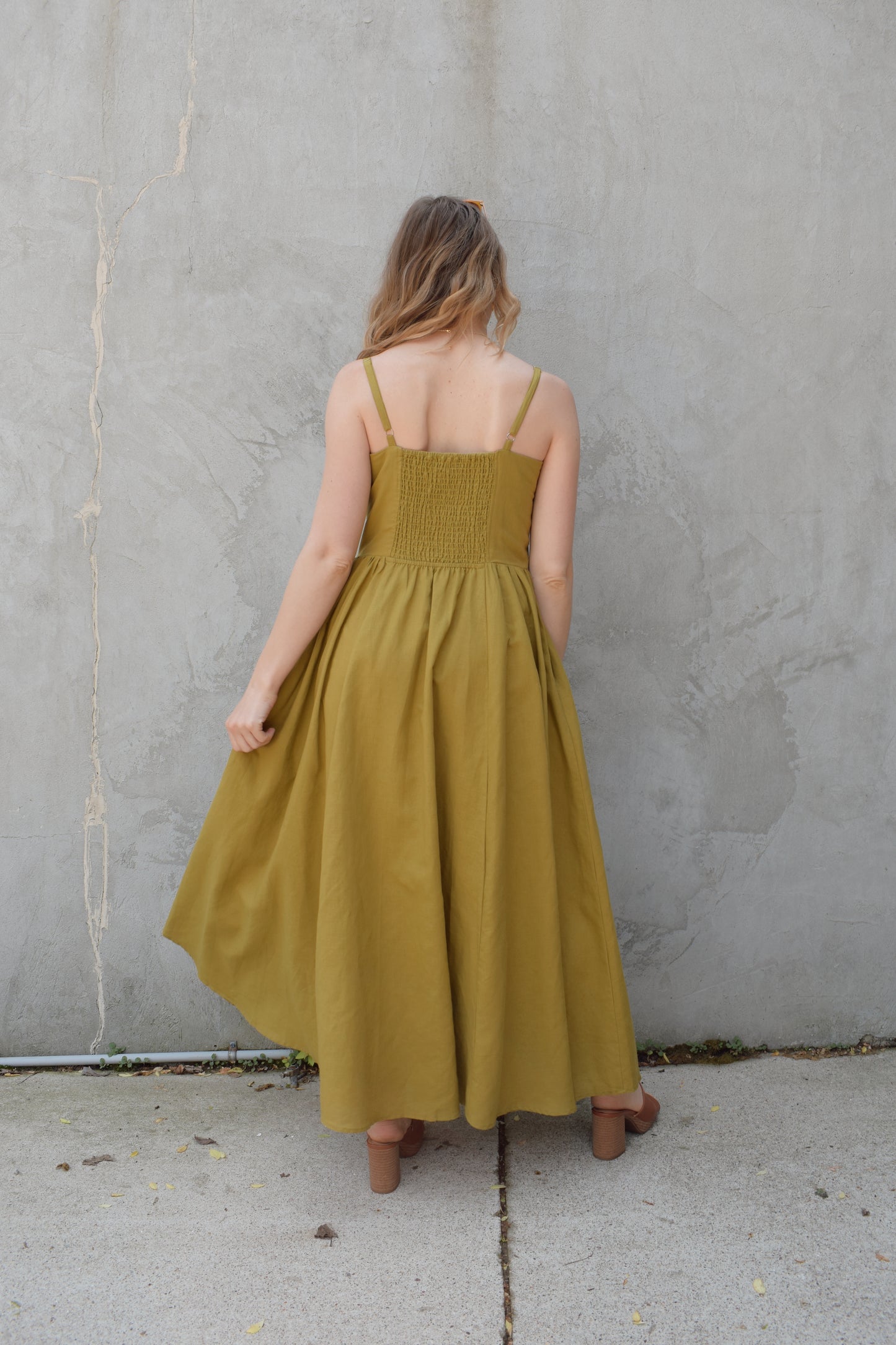 spaghetti strap midi dress with pleats at waistline fitted bodice buttons all down the front that are the same color as the dress, adjustable straps, has pockets, square neckline, smocked panel on back of bodice