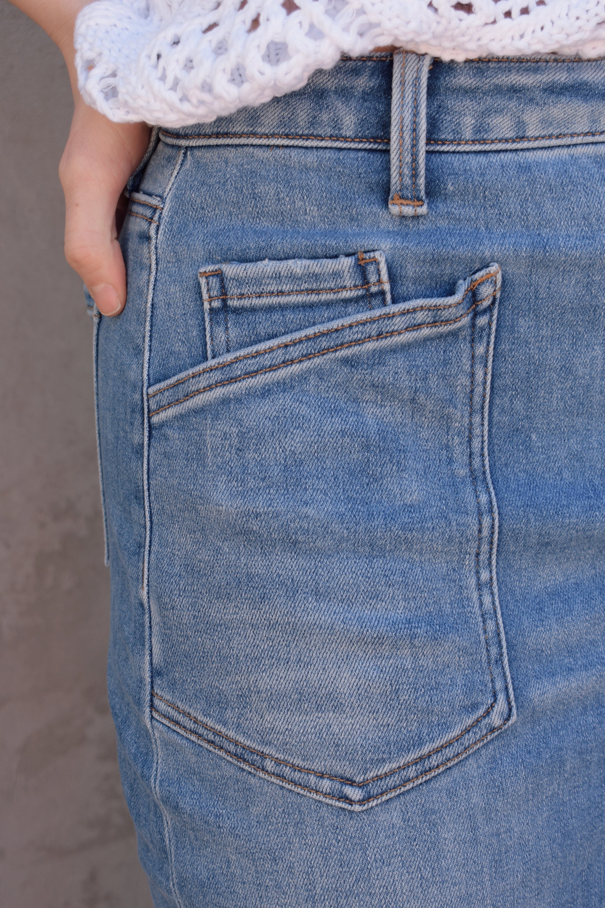 utility stretch denim midi skirt with front slit medium wash large patch pockets on front with angled entry has back pockets and belt loops zip and button enclosure