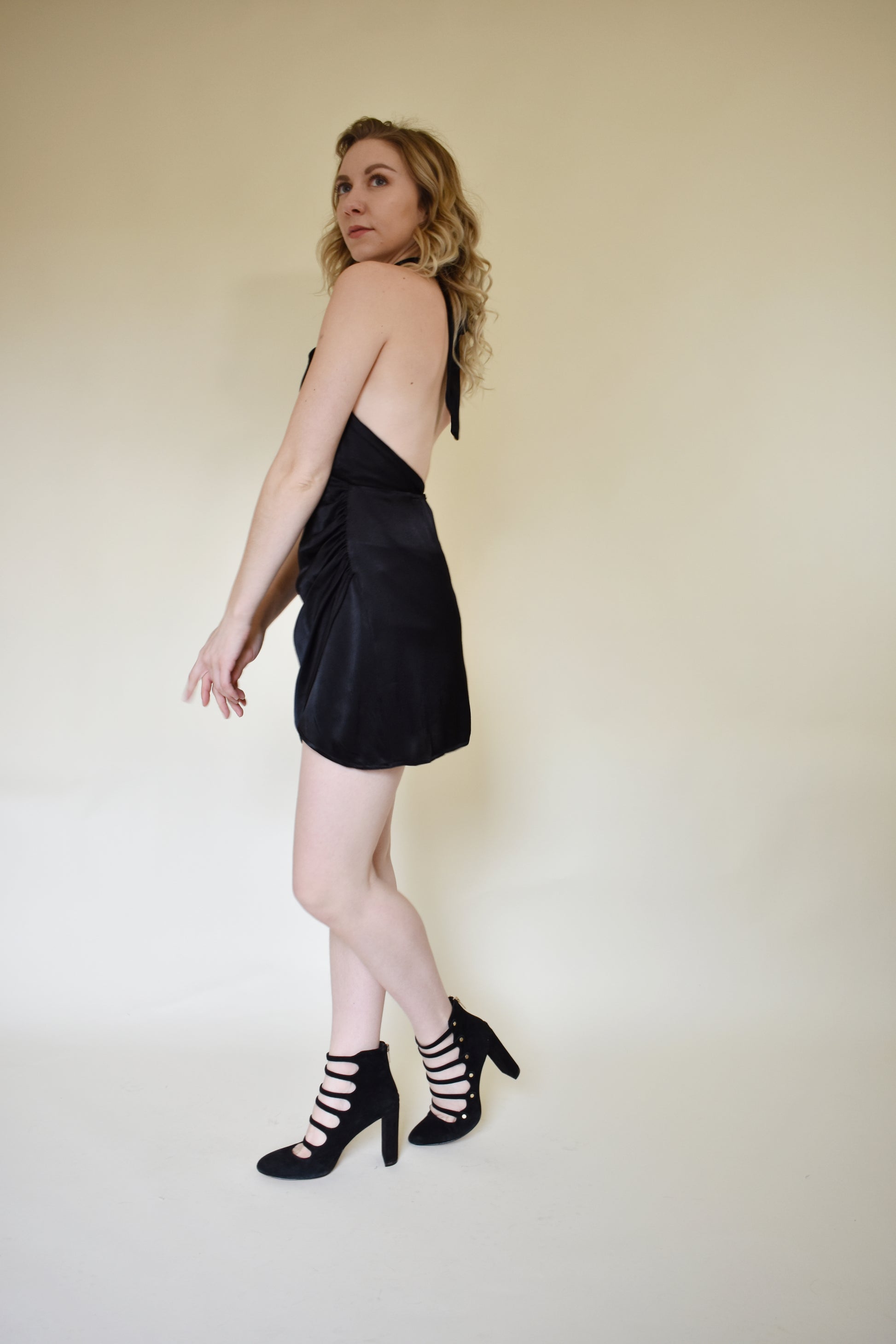 black satin mini dress with wrap hem, rushing at left side, zipper back enclosure, halter tie top that crosses in front.