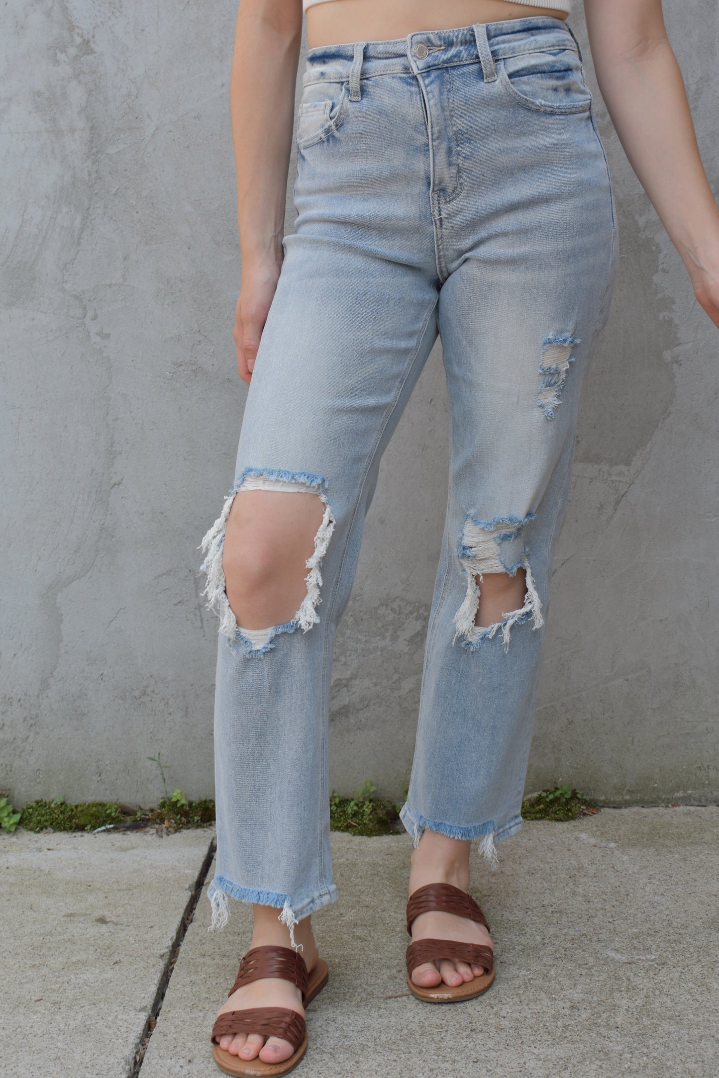 high rise stretch denim. ankle length with distressed hem. holes at the knees and distressing. straight fit. light wash.