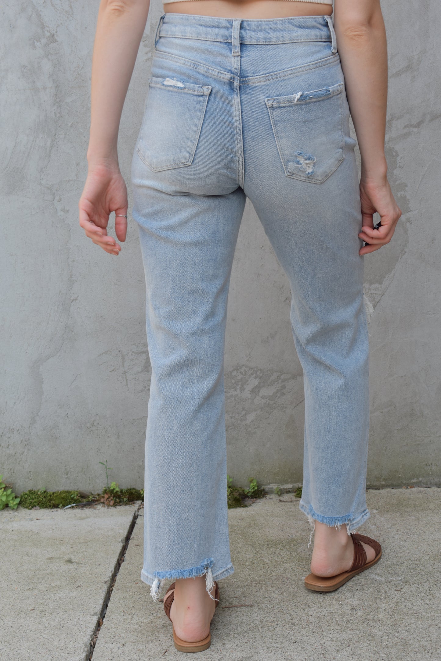 high rise stretch denim. ankle length with distressed hem. holes at the knees and distressing. straight fit. light wash.