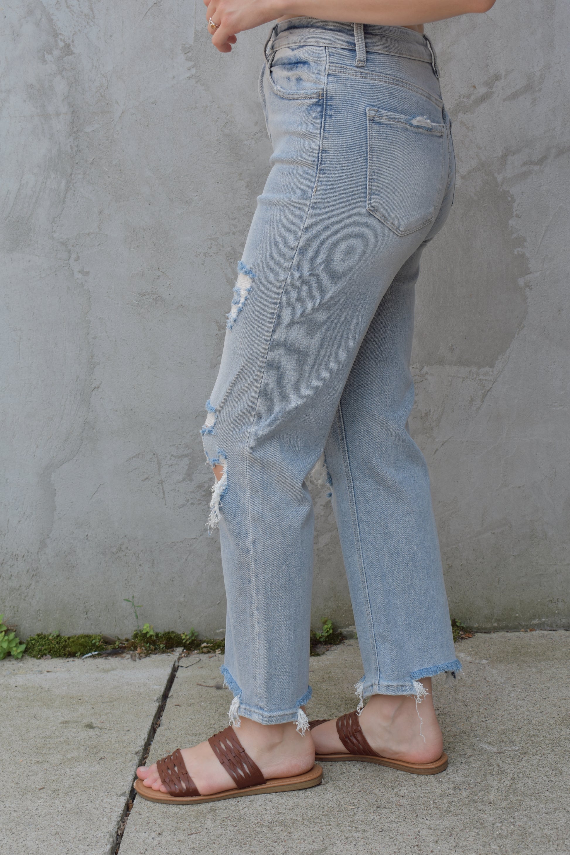 high rise stretch denim. ankle length with distressed hem. holes at the knees and distressing. straight fit. light wash.