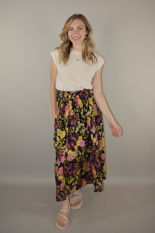 pink, yellow, green and neutral tone floral print on a black background. flowy lined midi skirt with side zip enclosure. fitted waist with no elastic. 