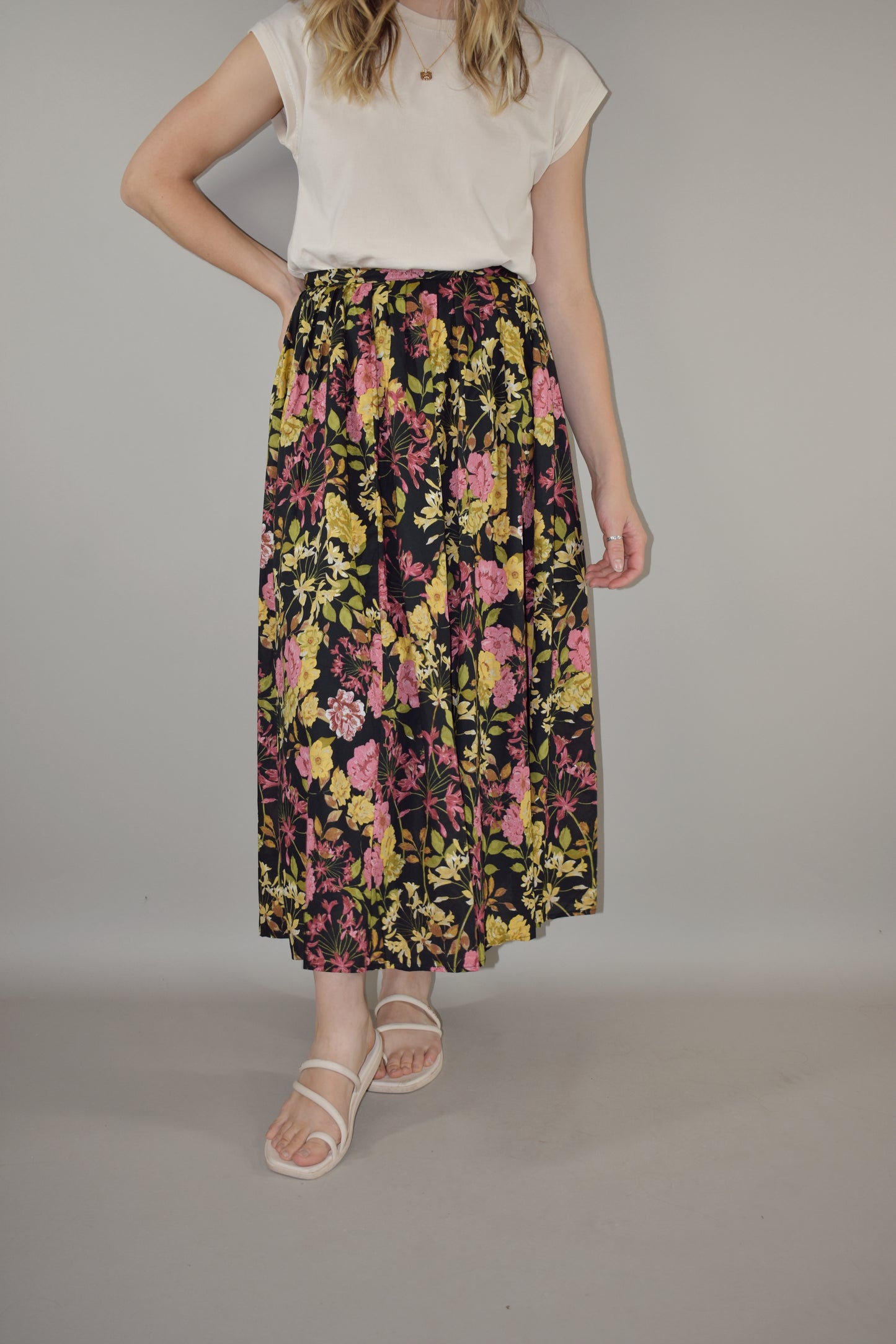 pink, yellow, green and neutral tone floral print on a black background. flowy lined midi skirt with side zip enclosure. fitted waist with no elastic. 