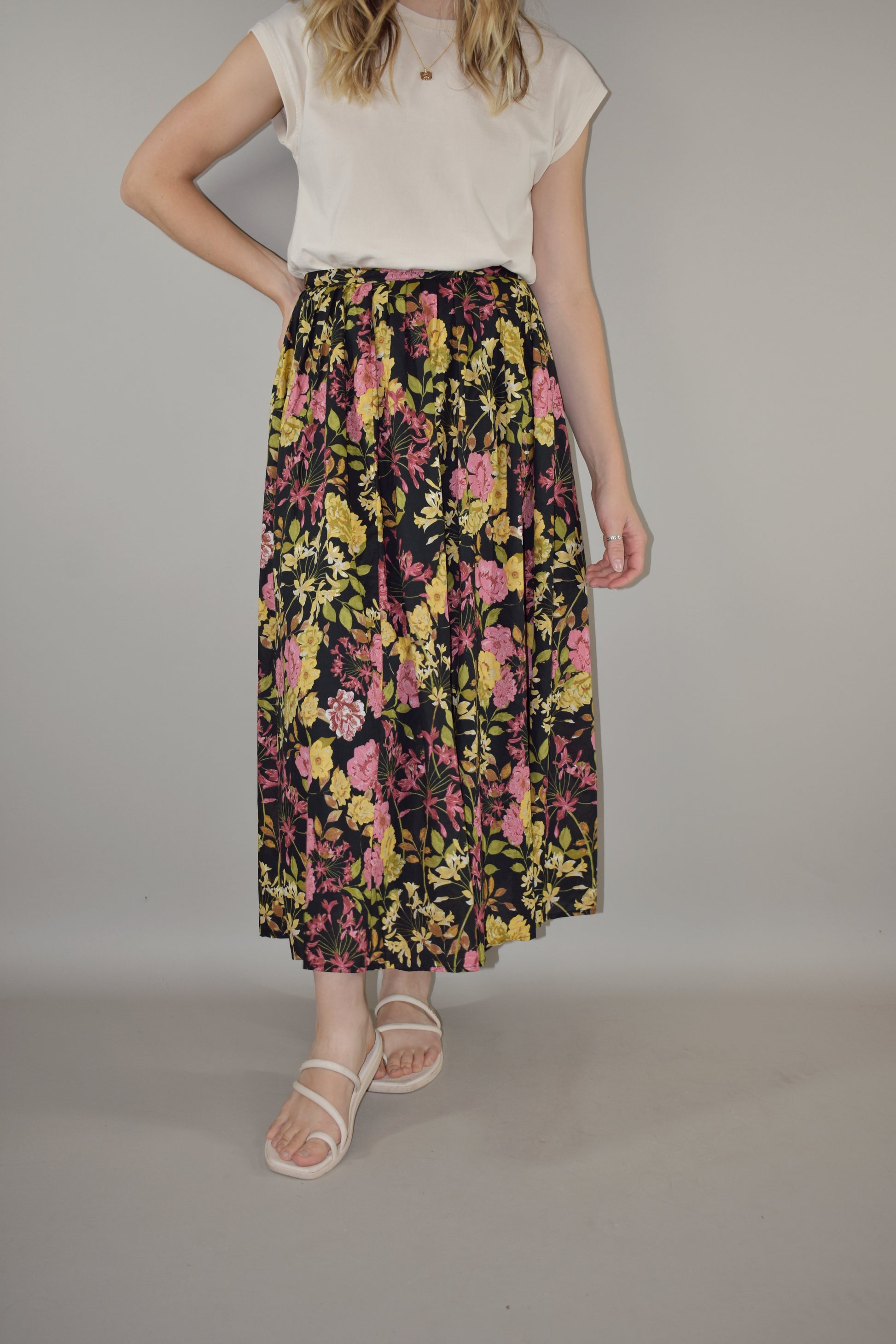 pink, yellow, green and neutral tone floral print on a black background. flowy lined midi skirt with side zip enclosure. fitted waist with no elastic. 