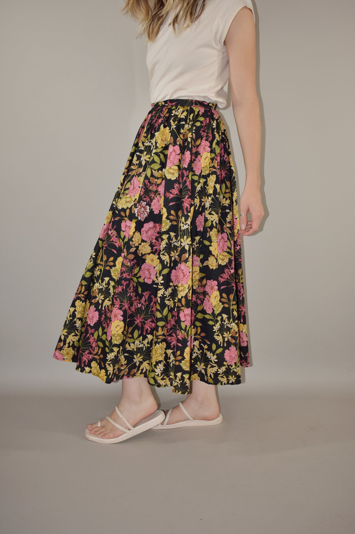 pink, yellow, green and neutral tone floral print on a black background. flowy lined midi skirt with side zip enclosure. fitted waist with no elastic. 