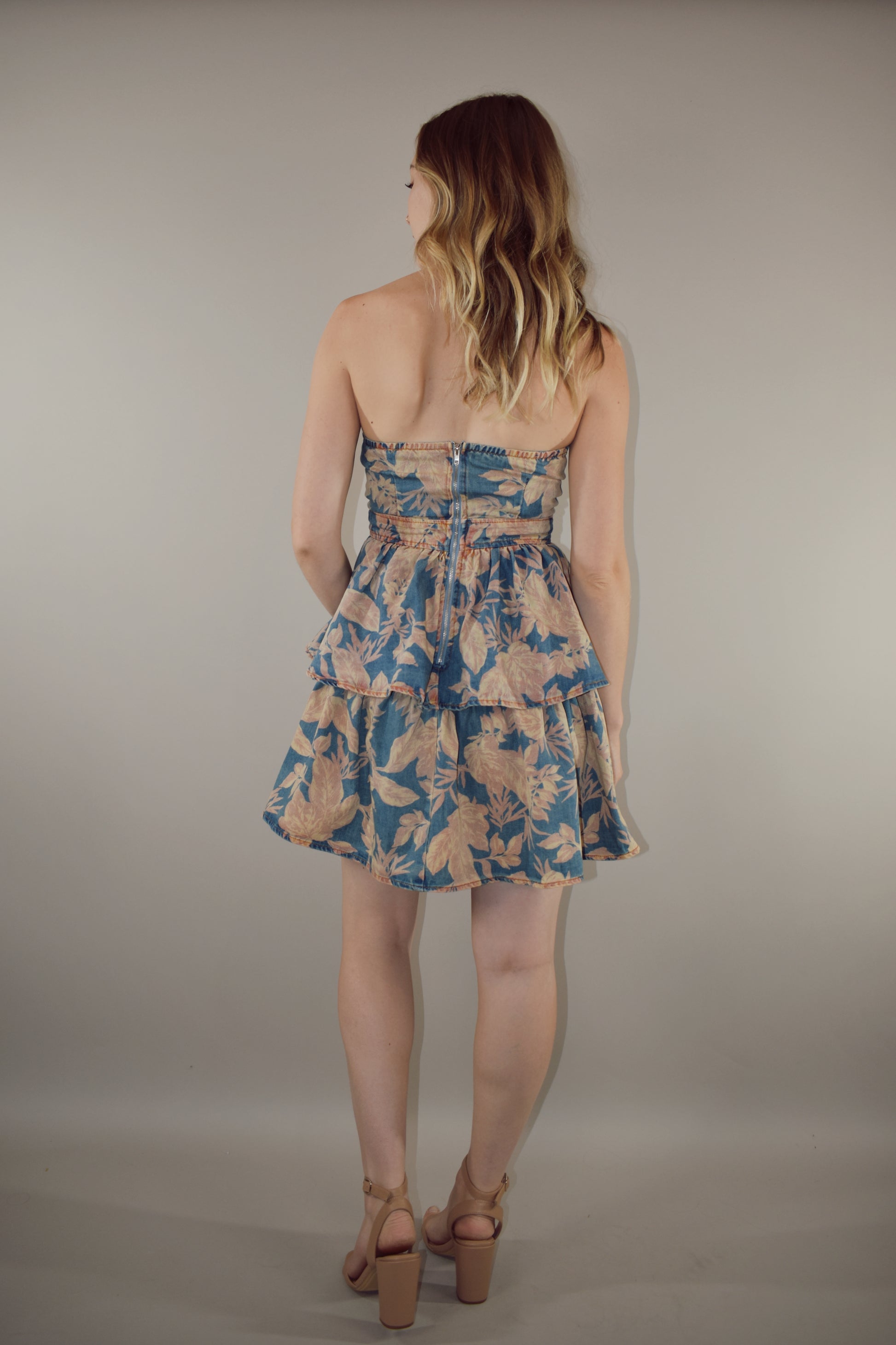 denim floral mini dress, strapless, fitted bodice, zip enclosure on back. tiered skirt, peachy tan floral pattern on light denim background.