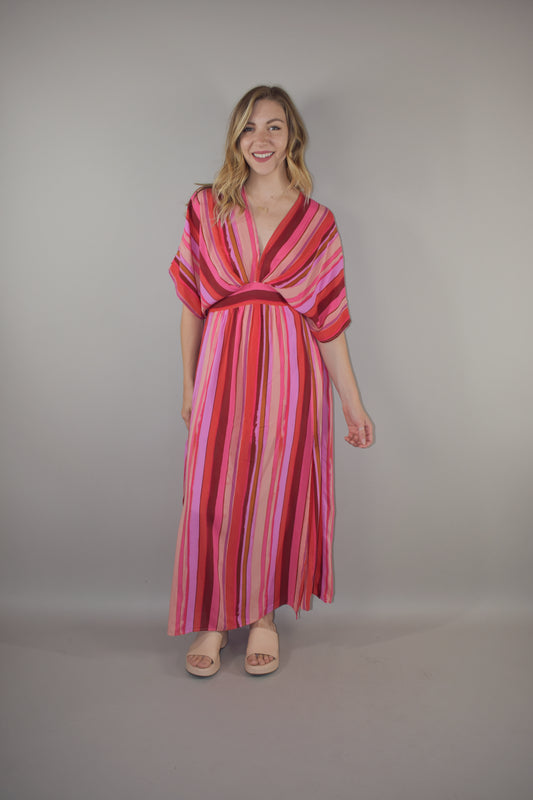 tones of red vertical striped maxi dress with flowy lightweight fabric, lined with a synched stretchy waistband and deep v neck with a hook and eye enclosure and dolman sleeves that hit at the elbow. side slits that are semi hidden unless walking. button enclosure at back neckline