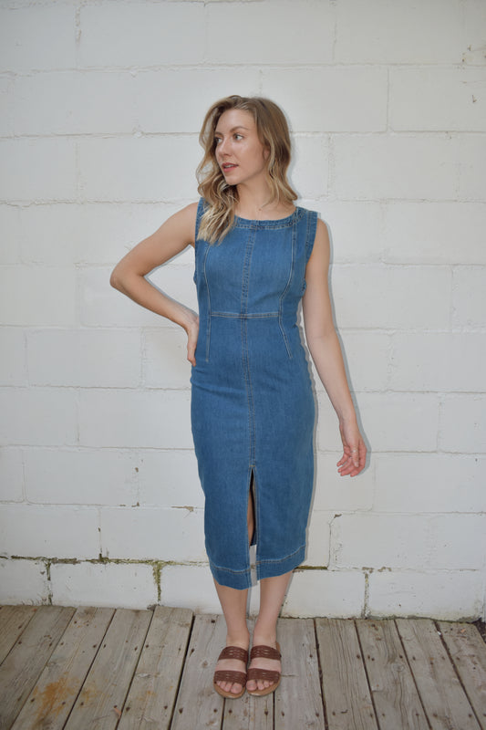 fitted midi length medium wash denim stretch dress. high scoop neck with zip back enclosure. seam detailing on bodice. slit up front of skirt.