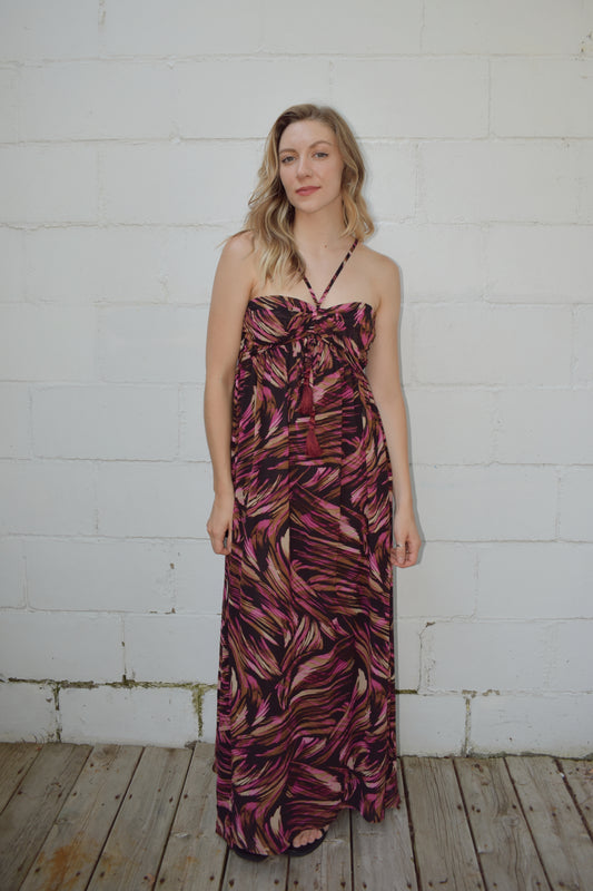 maxi dress with black background and a fuchsia wavy/swirl print. spaghetti straps cross and meet in middle of front with synched bra area with tassel. adjustable straps 