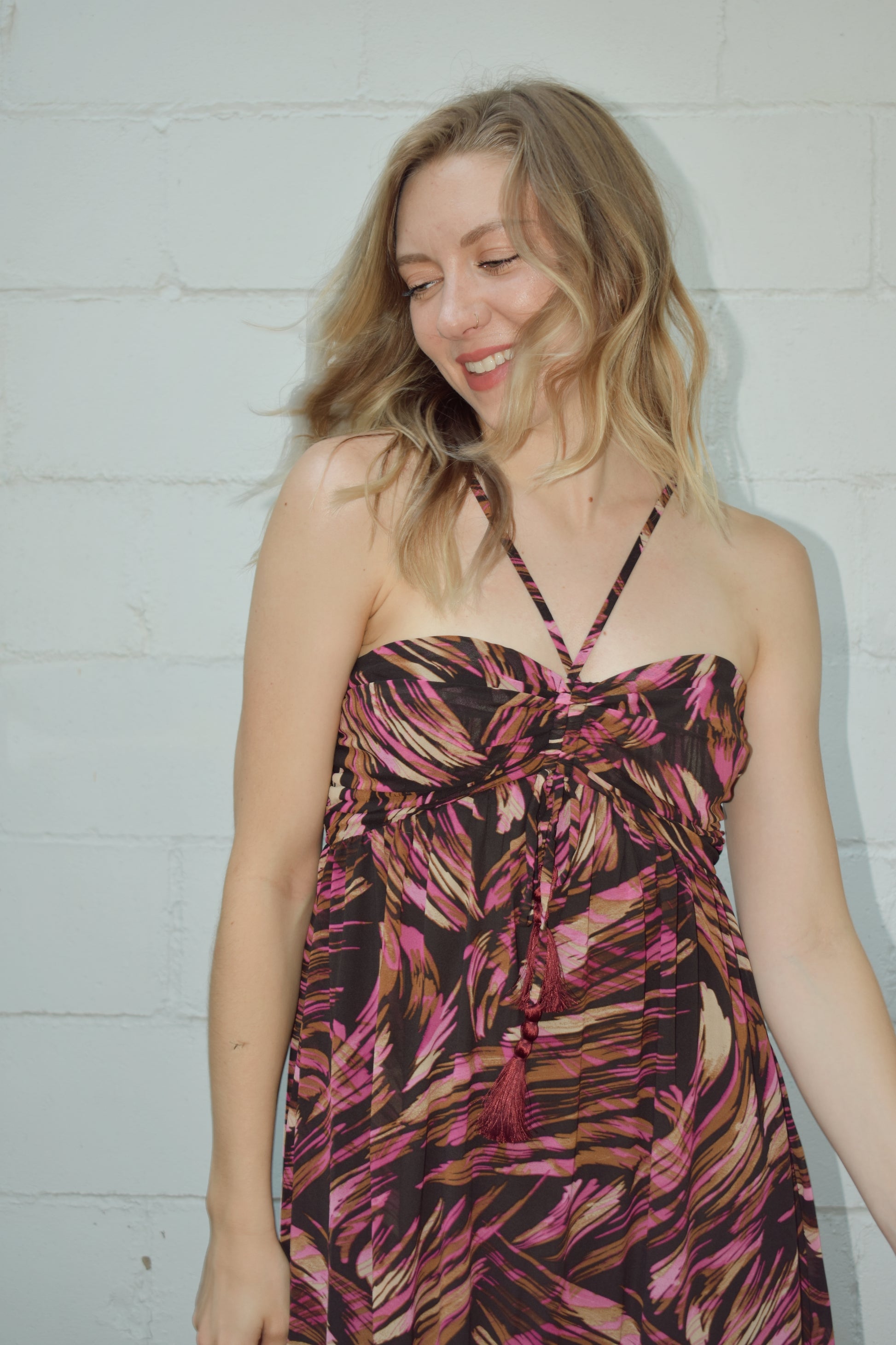 maxi dress with black background and a fuchsia wavy/swirl print. spaghetti straps cross and meet in middle of front with synched bra area with tassel. adjustable straps 