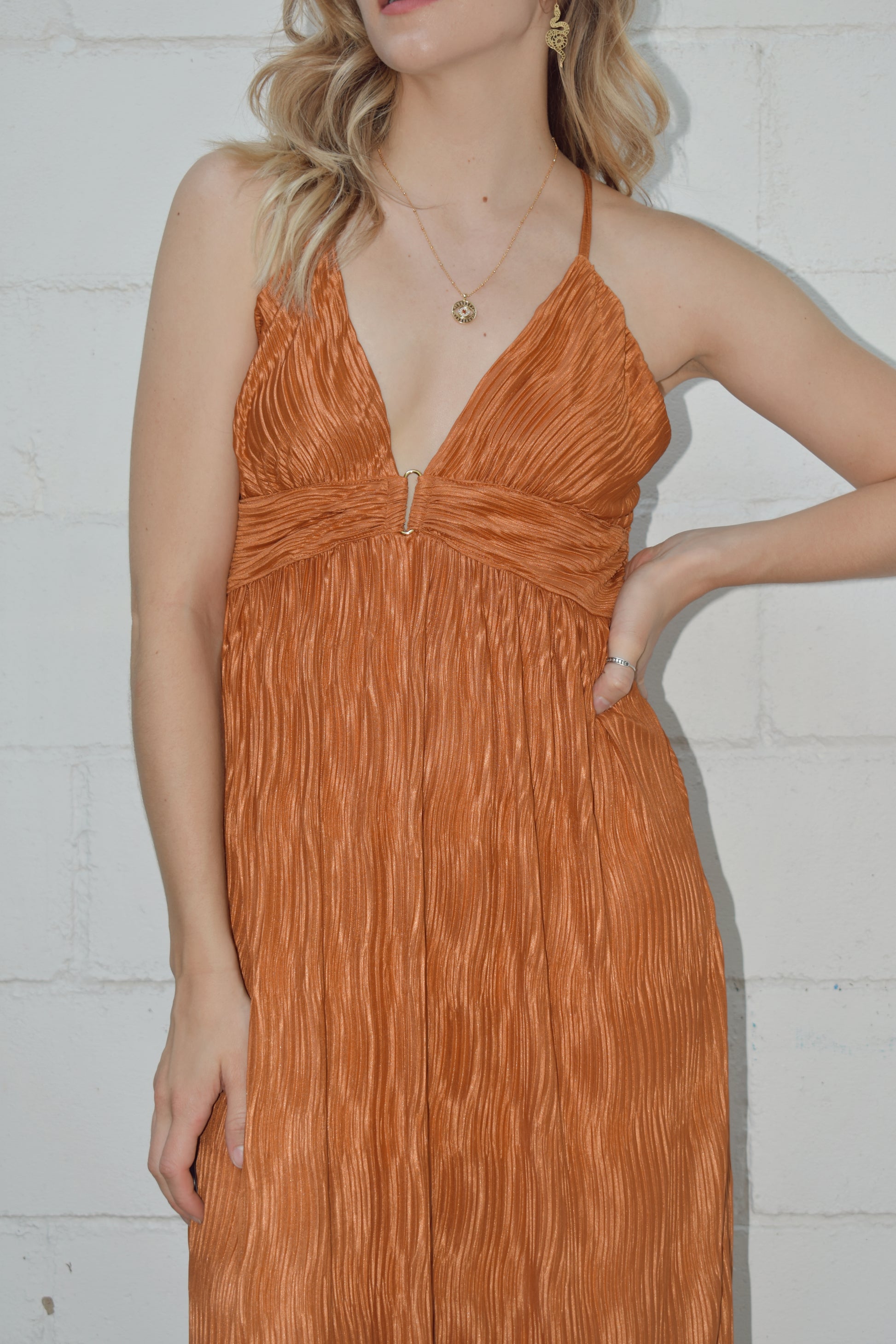 deep v neck spaghetti strap dress with a wavy texture fabric that illuminates when in the sun. maxi dress. straps cross in the back and tie which features a triangle cutout. theres a metal bar that connects the band just under the neckline.