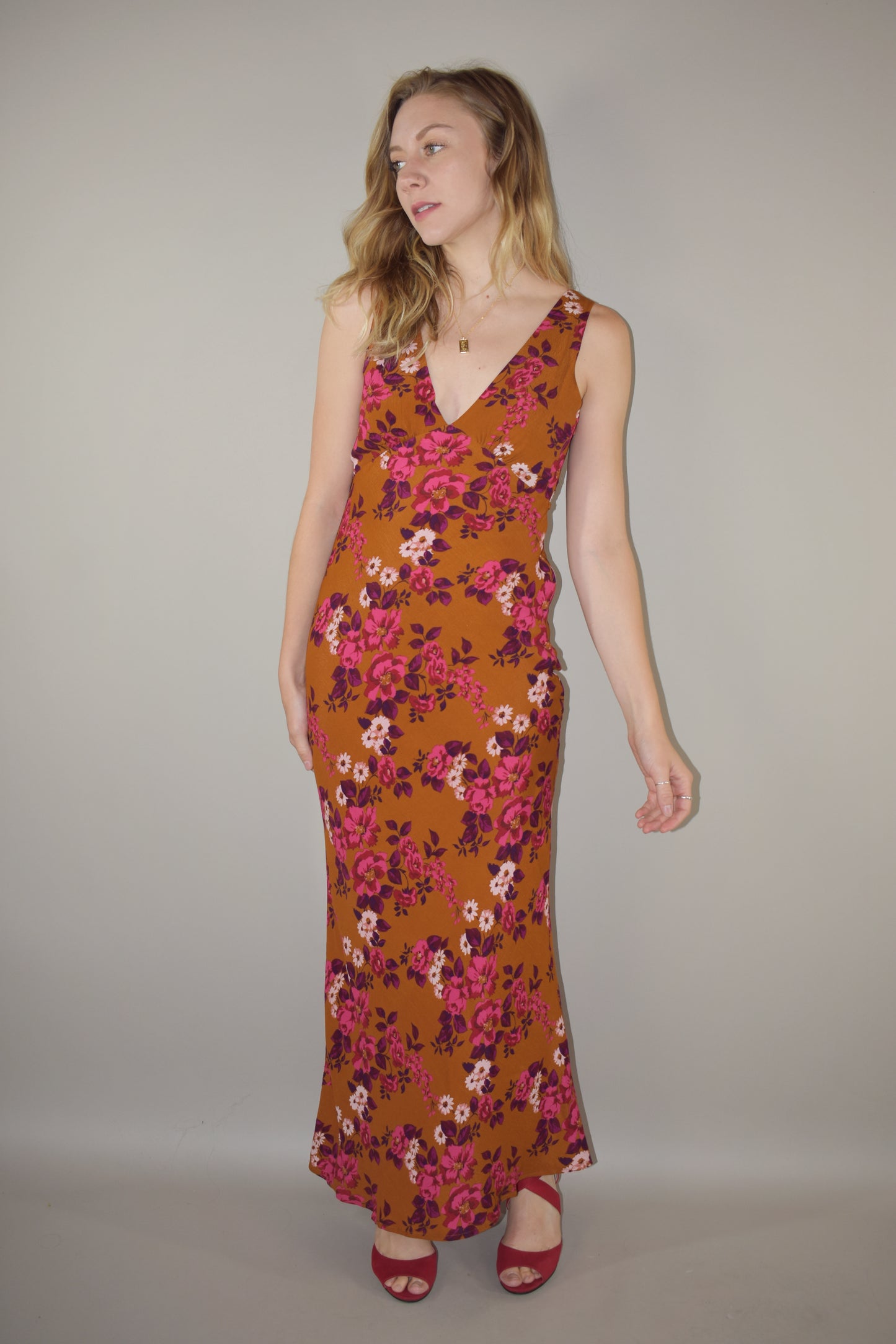 elegant floral maxi dress, v front and back neckline, more fitted through bodice and hips, skinny tie at waist that ties in the back, hidden side zip enclosure. Rust, pink, plum, fuchsia and white colors.