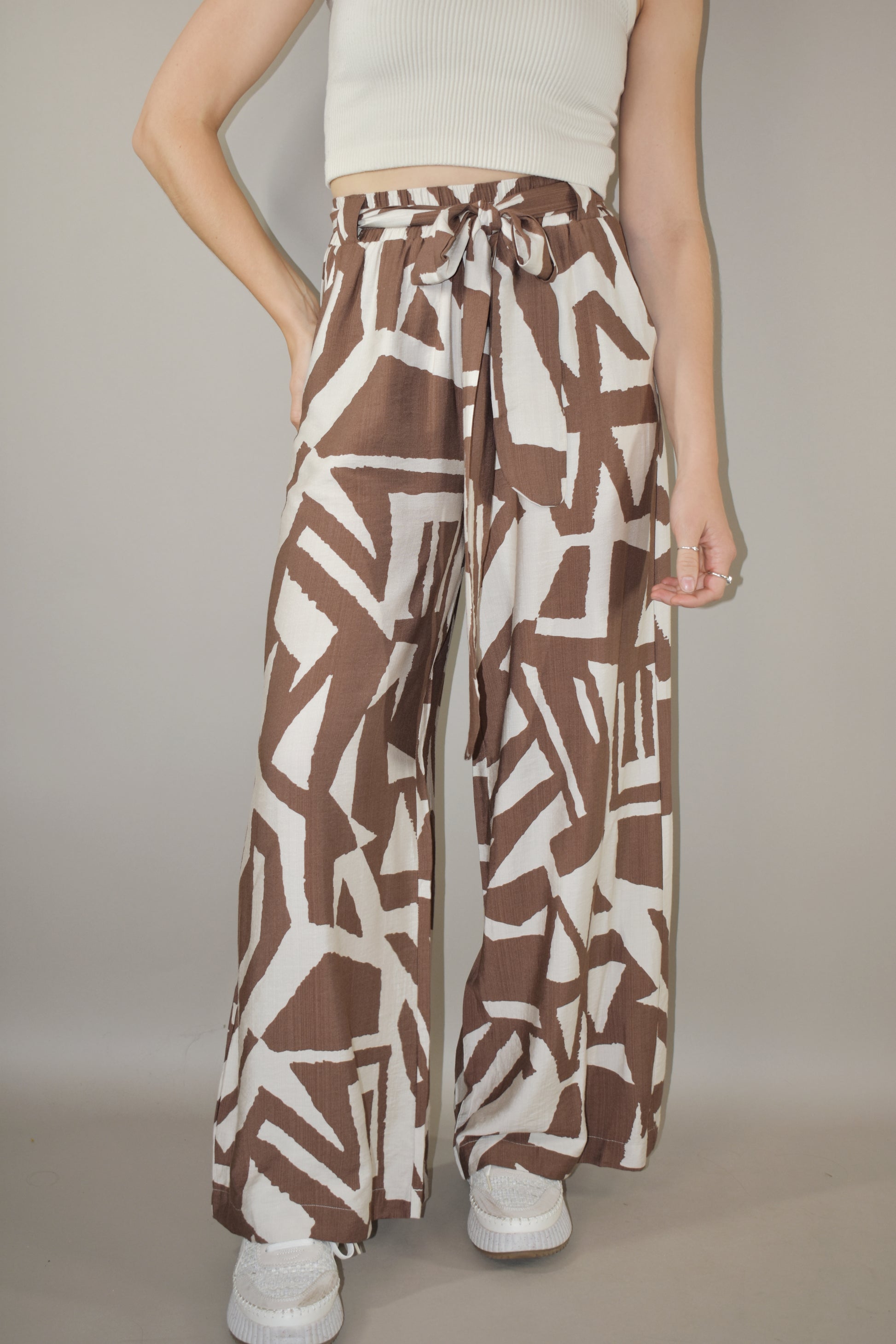 wide leg high waisted belted tie waist pants. flowy light weight fabric. cream and light brown geometric print. has pockets. full length.