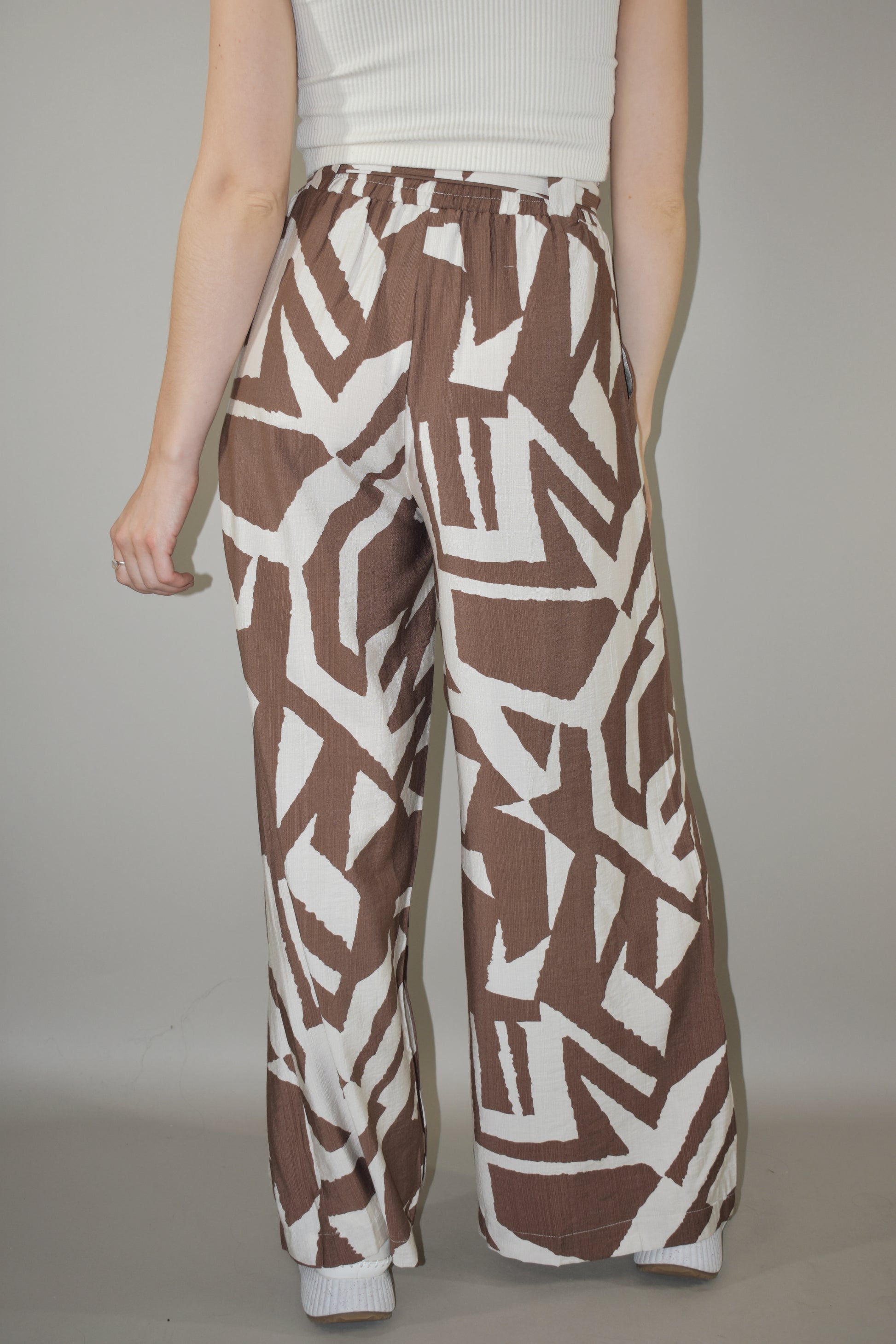 wide leg high waisted belted tie waist pants. flowy light weight fabric. cream and light brown geometric print. has pockets. full length.