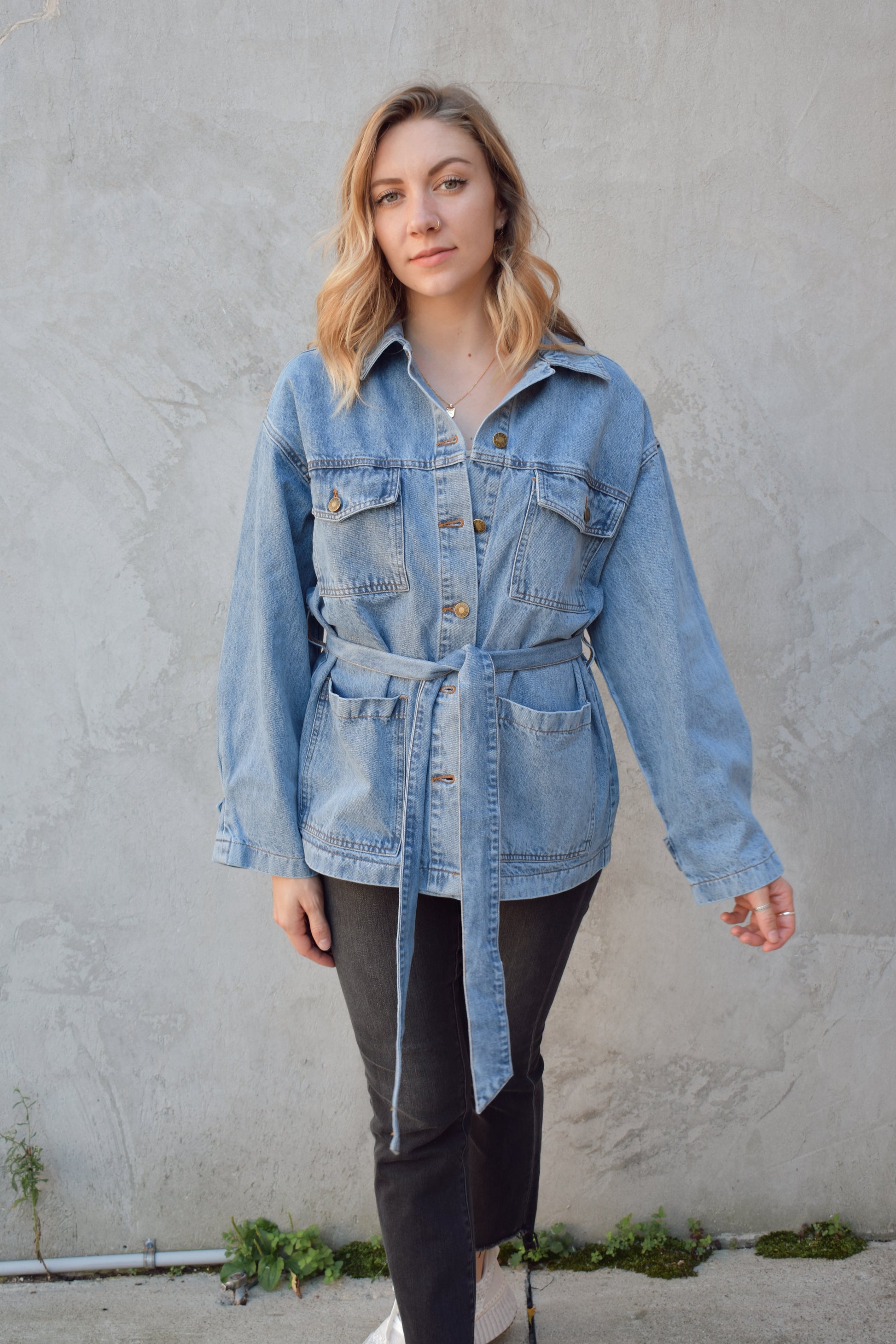 medium wash denim jacket with relaxed fit, tie at waist, deep patch pockets along with breast pockets with flap and button enclosure