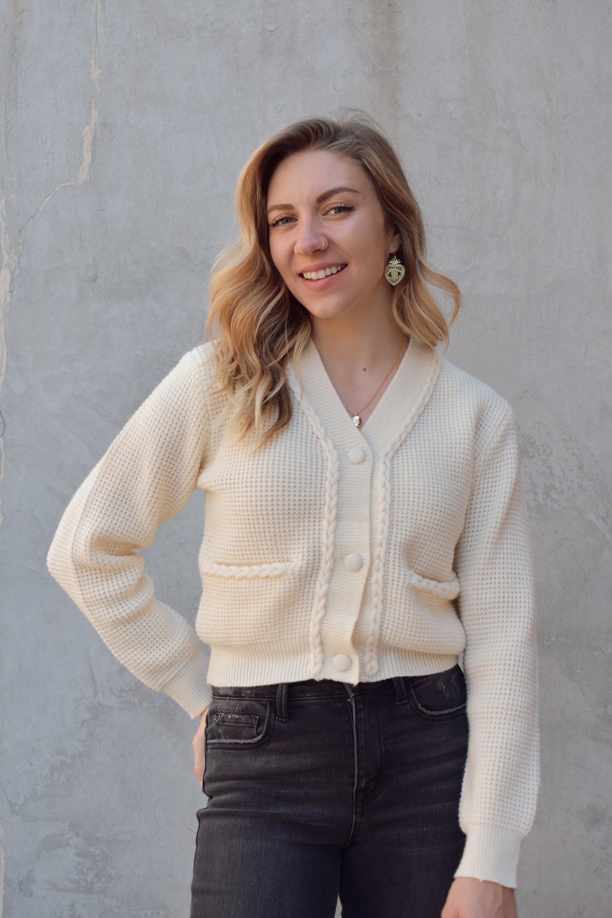 cropped cardigan with braided detailing along the front by the opening and along the pocket openings. knit fabric. 3 fabric buttons. v neck. 