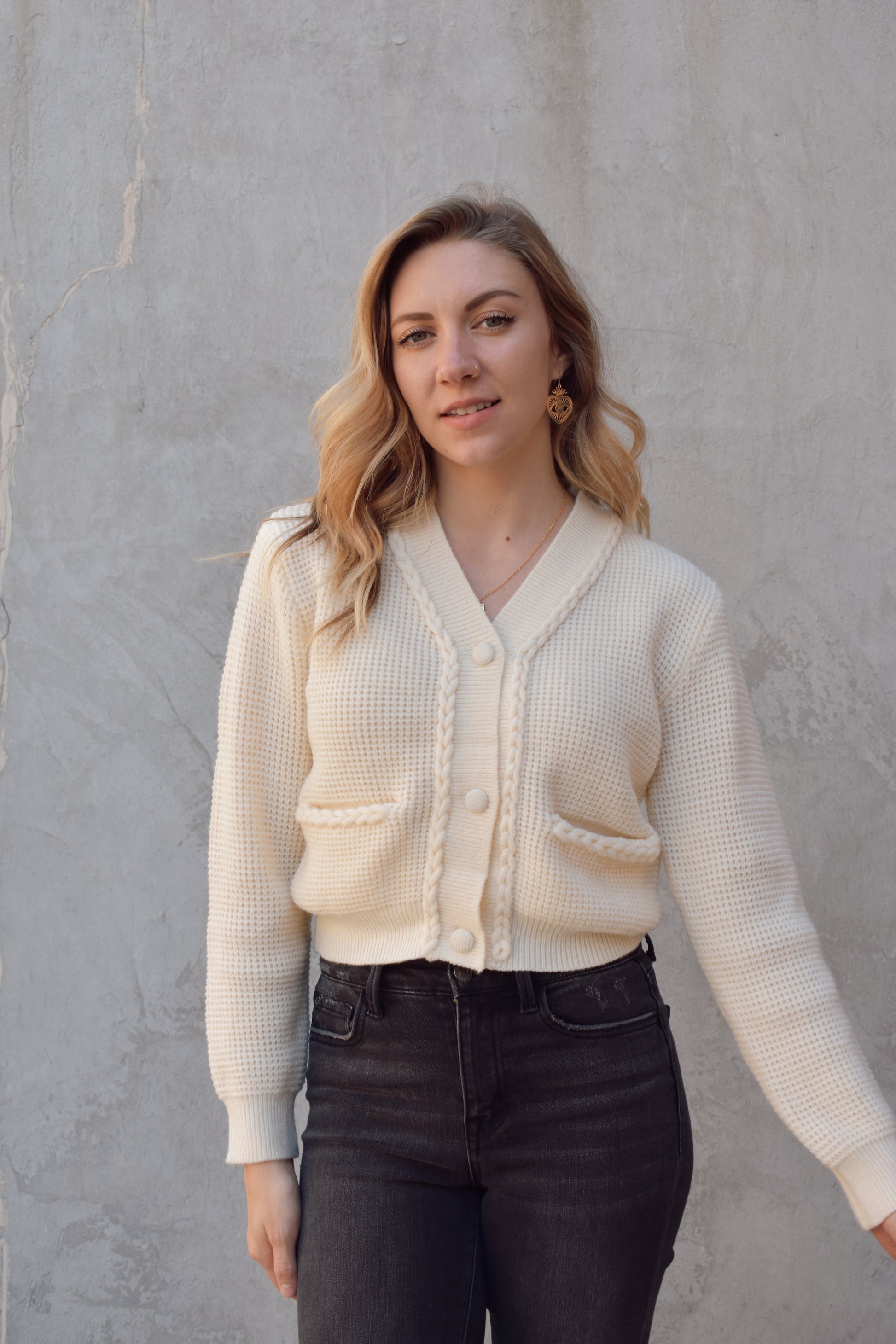 cropped cardigan with braided detailing along the front by the opening and along the pocket openings. knit fabric. 3 fabric buttons. v neck. 