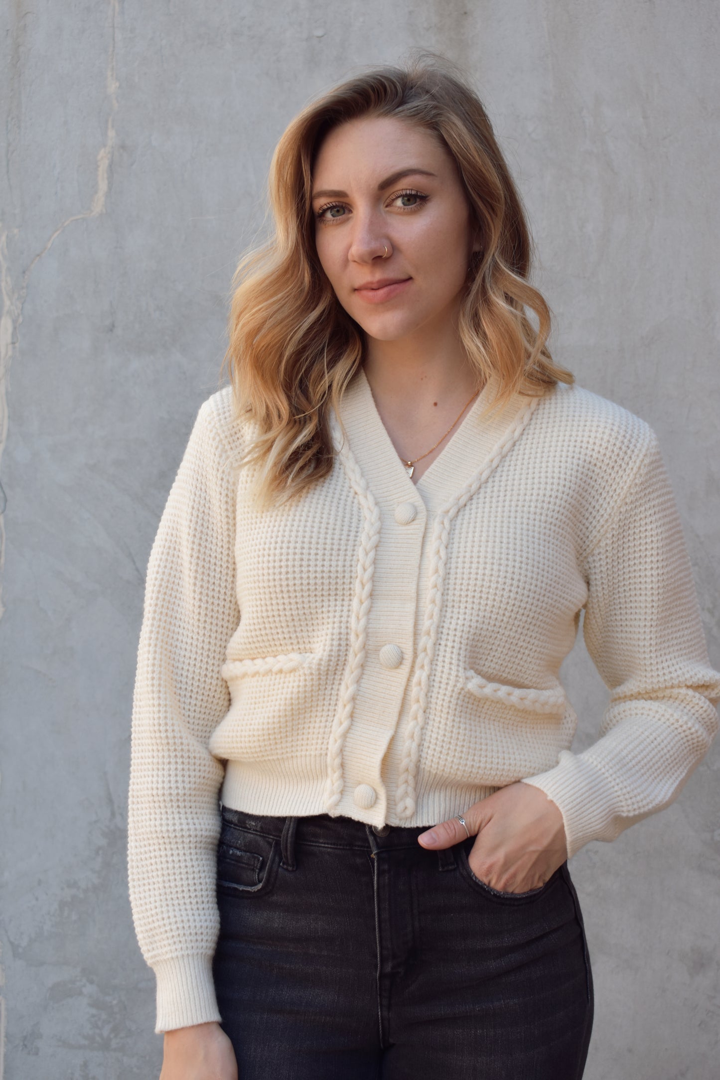 cropped cardigan with braided detailing along the front by the opening and along the pocket openings. knit fabric. 3 fabric buttons. v neck. 