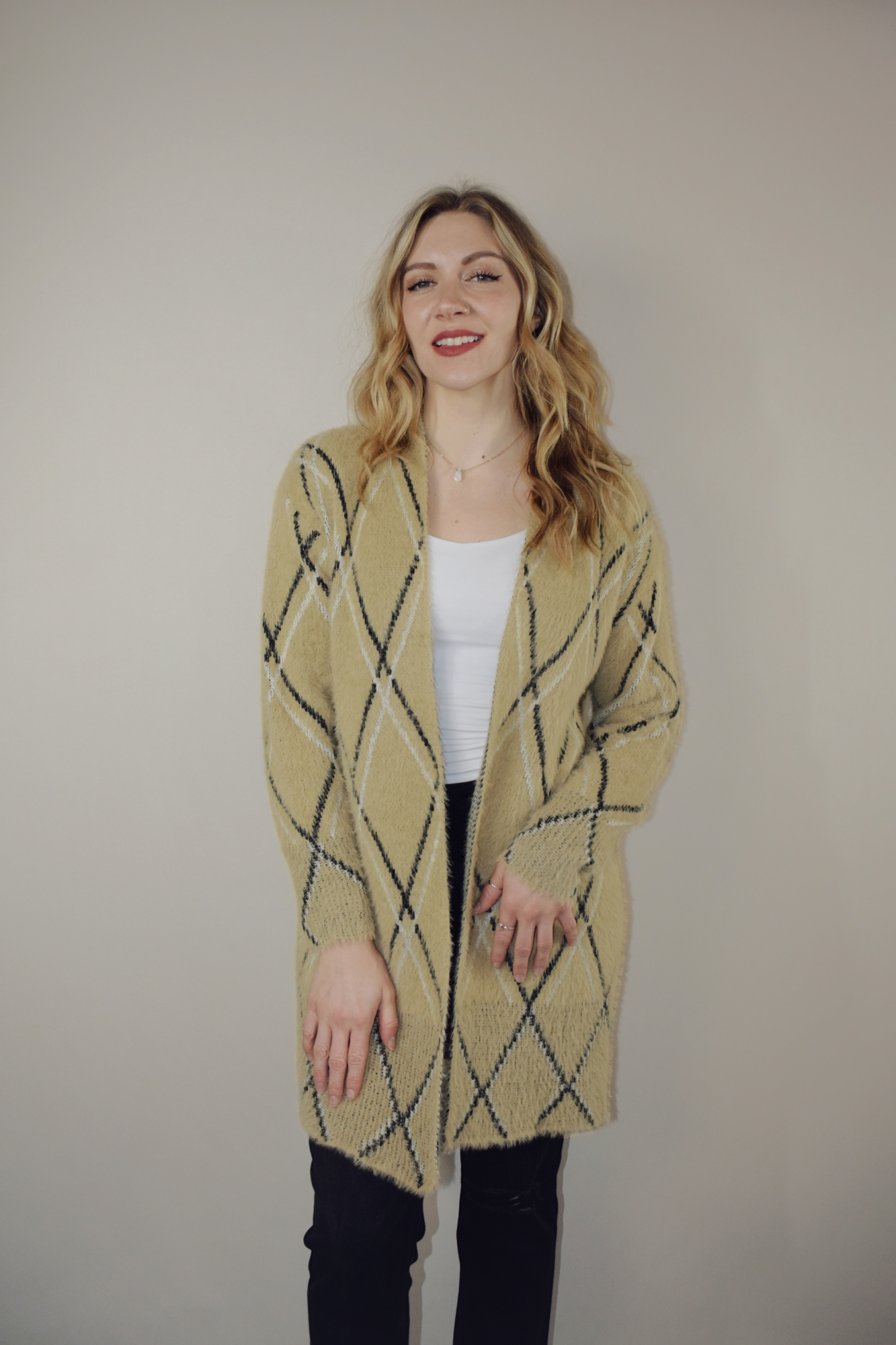 super plush open cardigan with tan background and black and white lined diamond design. hits at mid thigh.