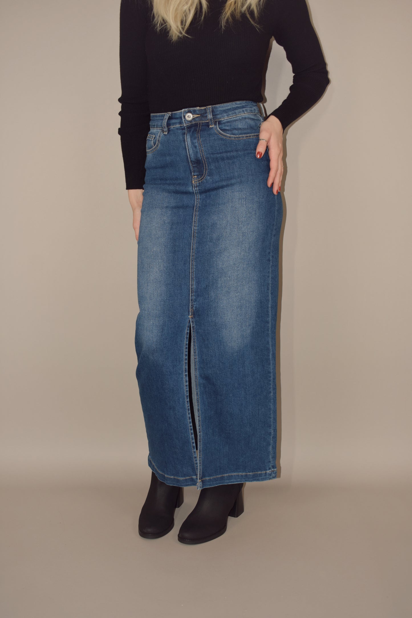 denim midi skirt that is more full length than midi and has a front slit with front and back pockets and is high waisted. made of stretch denim and is a medium dark wash.